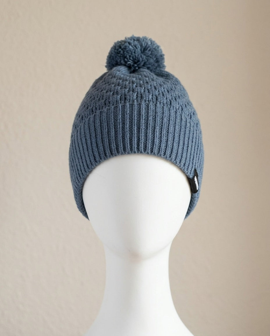 Bonnet Twentyfour bleu orage à pompon, vue de face sur mannequin – Frippin'Dealz – photo retouchée par IA