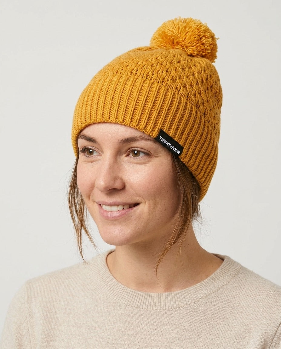 Bonnet Twentyfour moutarde à pompon porté – photo générée par IA