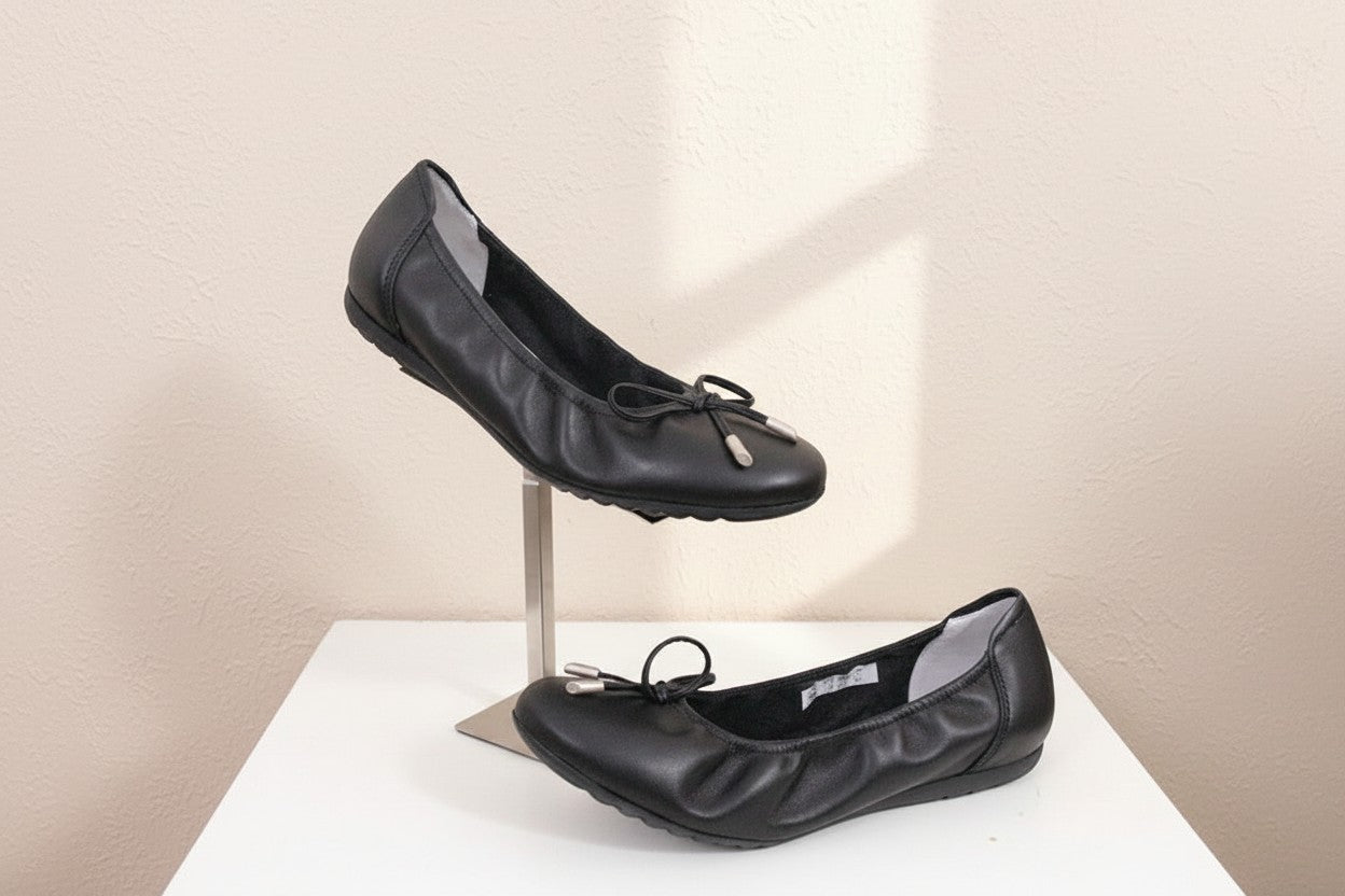 Ballerines Frippindealz SABRINAS en cuir noir avec nœud décoratif et embouts métalliques sur un présentoir