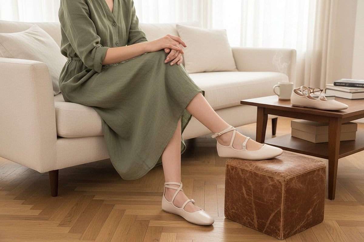 Femme portant des ballerines Mary Jane crème Bellucci avec brides croisées, assise sur un canapé dans un salon