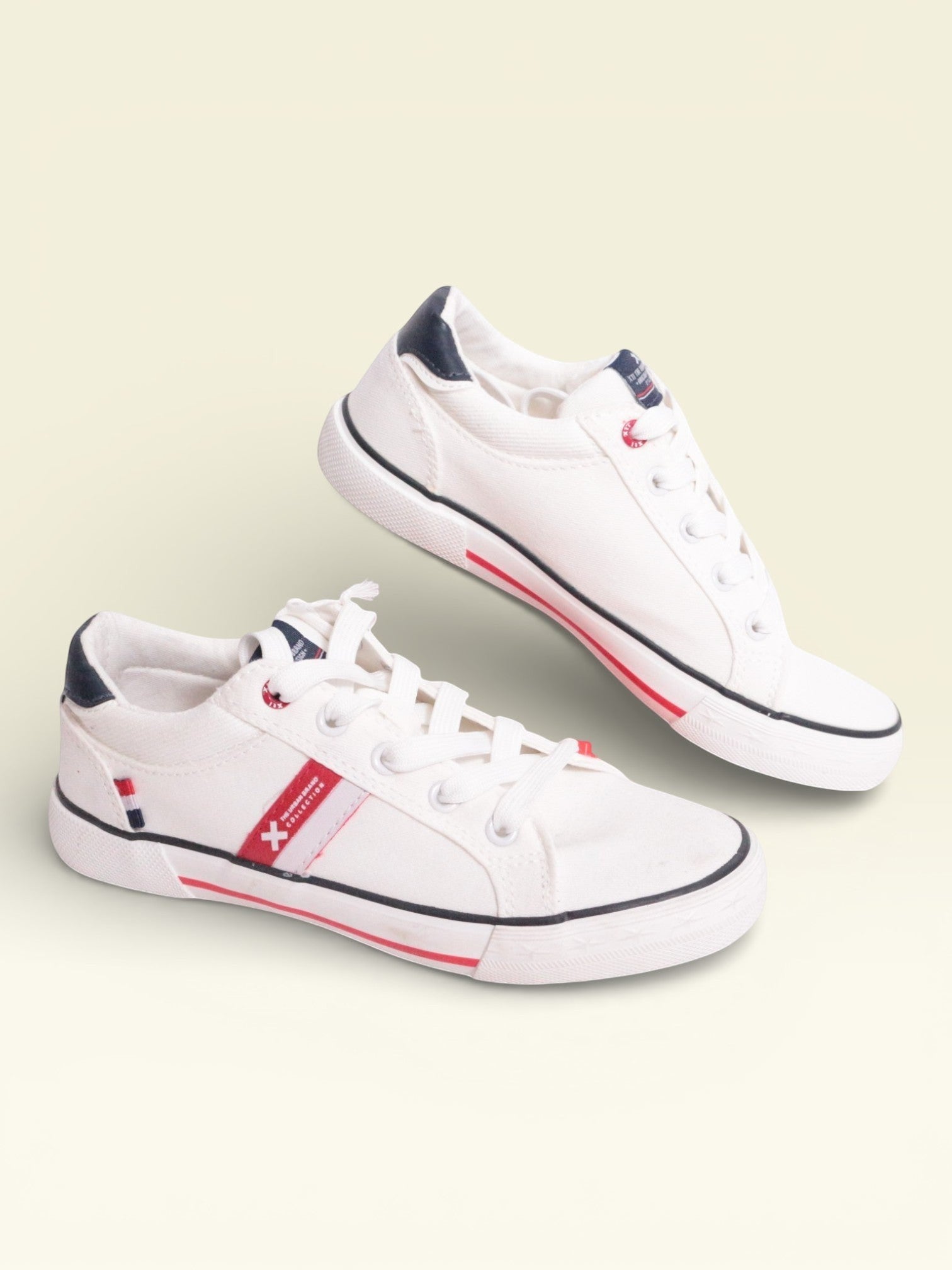 Frippindealz Baskets blanches en textile pour enfants avec détails rouges et semelles noires. Fermeture à lacets.