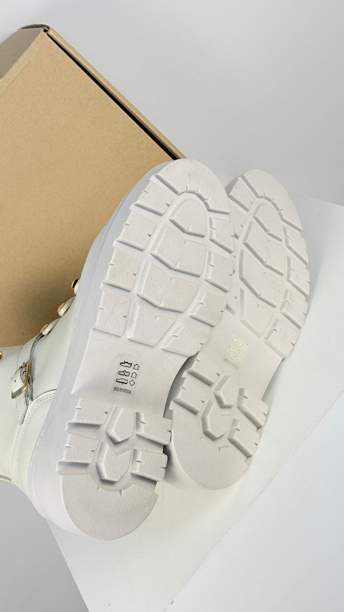 Semelles crantées antidérapantes des bottes Frippindealz en cuir beige avec détails dorés, vue de dessous