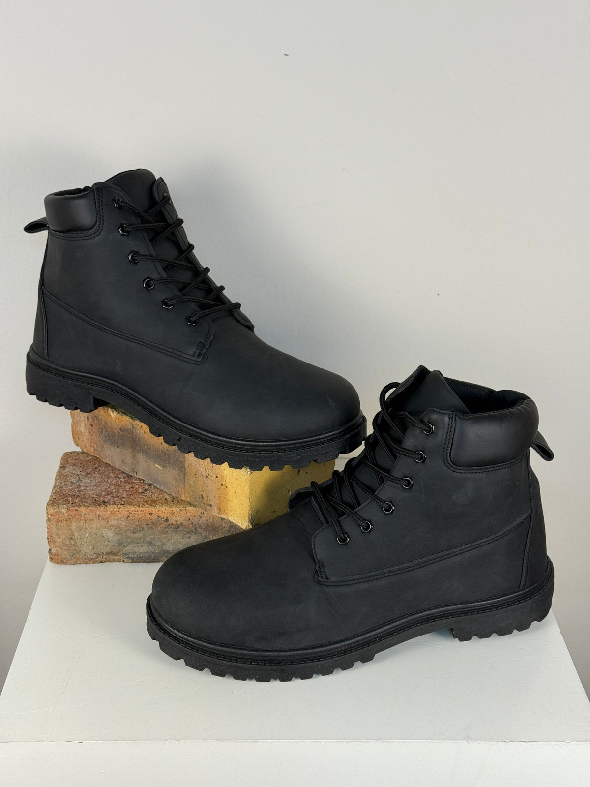 Bottes Frippindealz noires pour homme en cuir synthétique avec semelles épaisses crantées, style randonnée robuste.