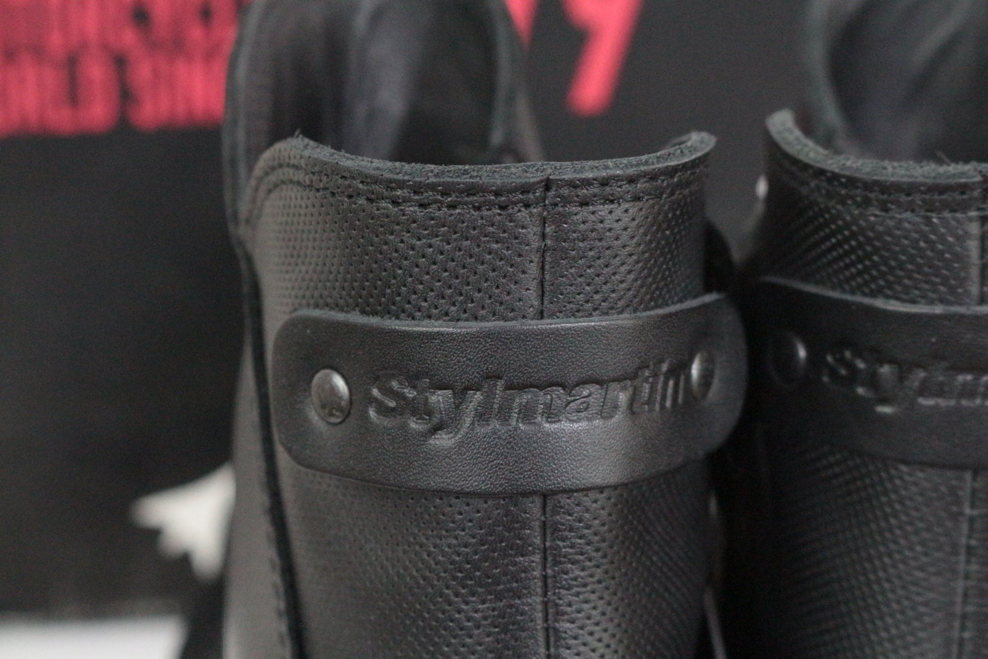 Gros plan sur le talon en cuir noir texturé des bottines moto femme Frippindealz Stylmartin avec logo embossé