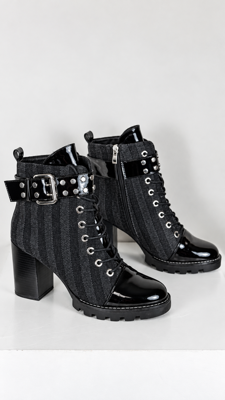 Bottines Frippindealz noires à talons hauts, cuir synthétique verni, lacets, zip et boucle cloutée décorative.