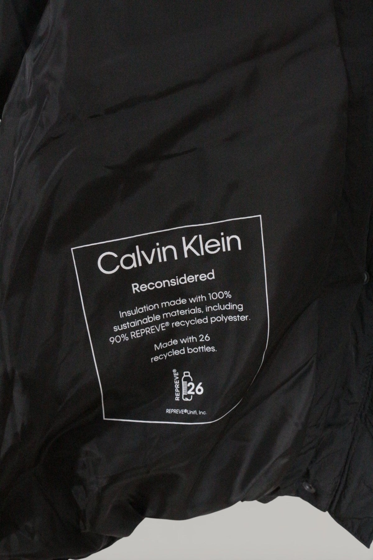 Étiquette intérieure Frippindealz d'une doudoune noire Calvin Klein en polyester recyclé REPREVE