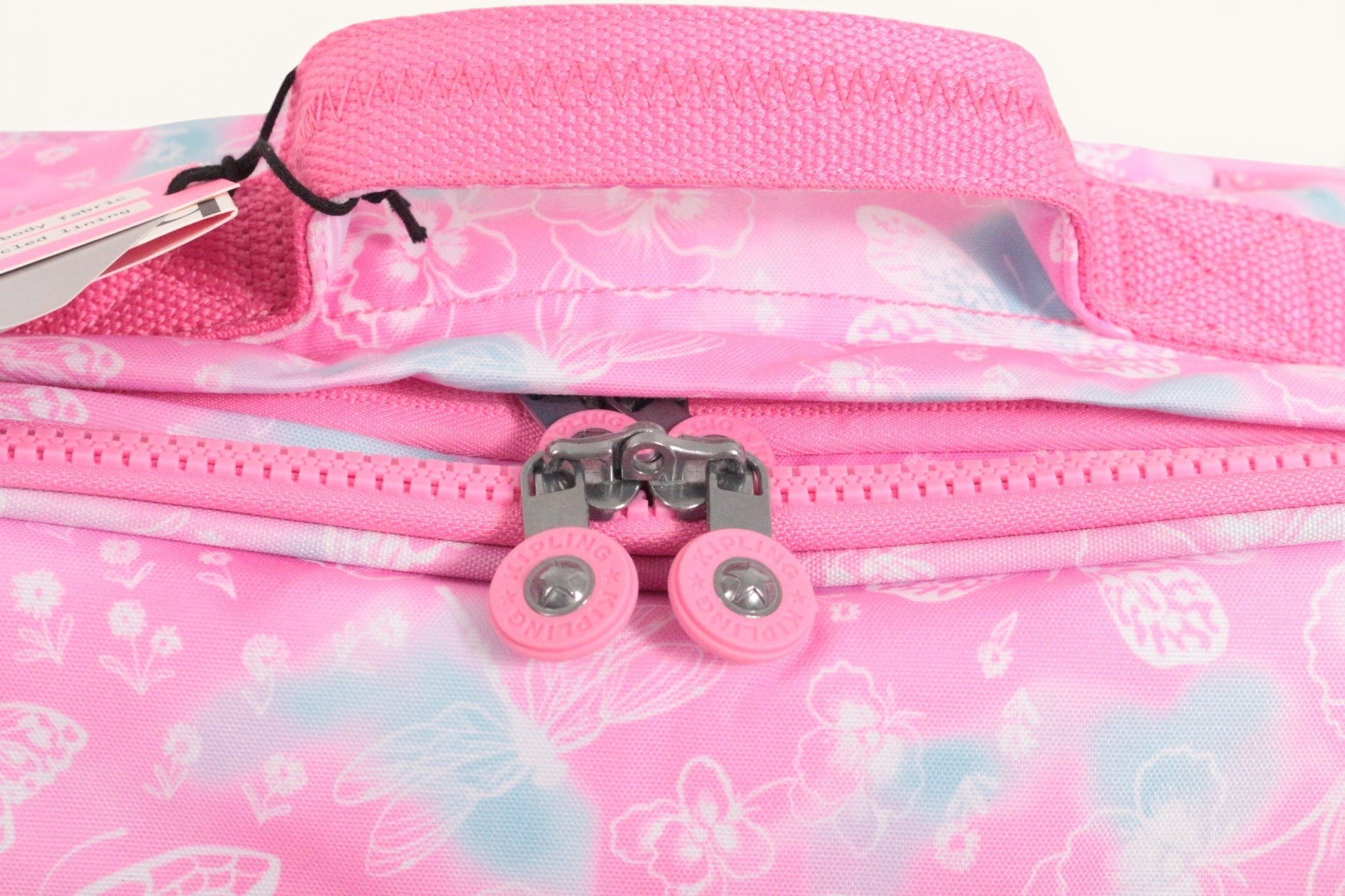 Détail du cartable Frippindealz Kipling New Storia rose à motifs fleurs et papillons avec poignée et fermetures zippées