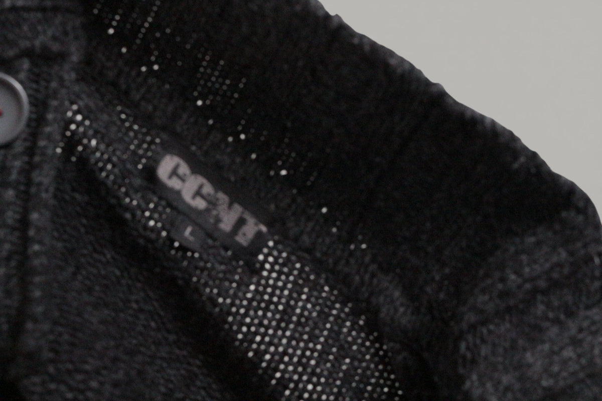 Gros plan sur l'étiquette de marque CCNT à l'intérieur d'un pull en acrylique gris foncé de Frippindealz