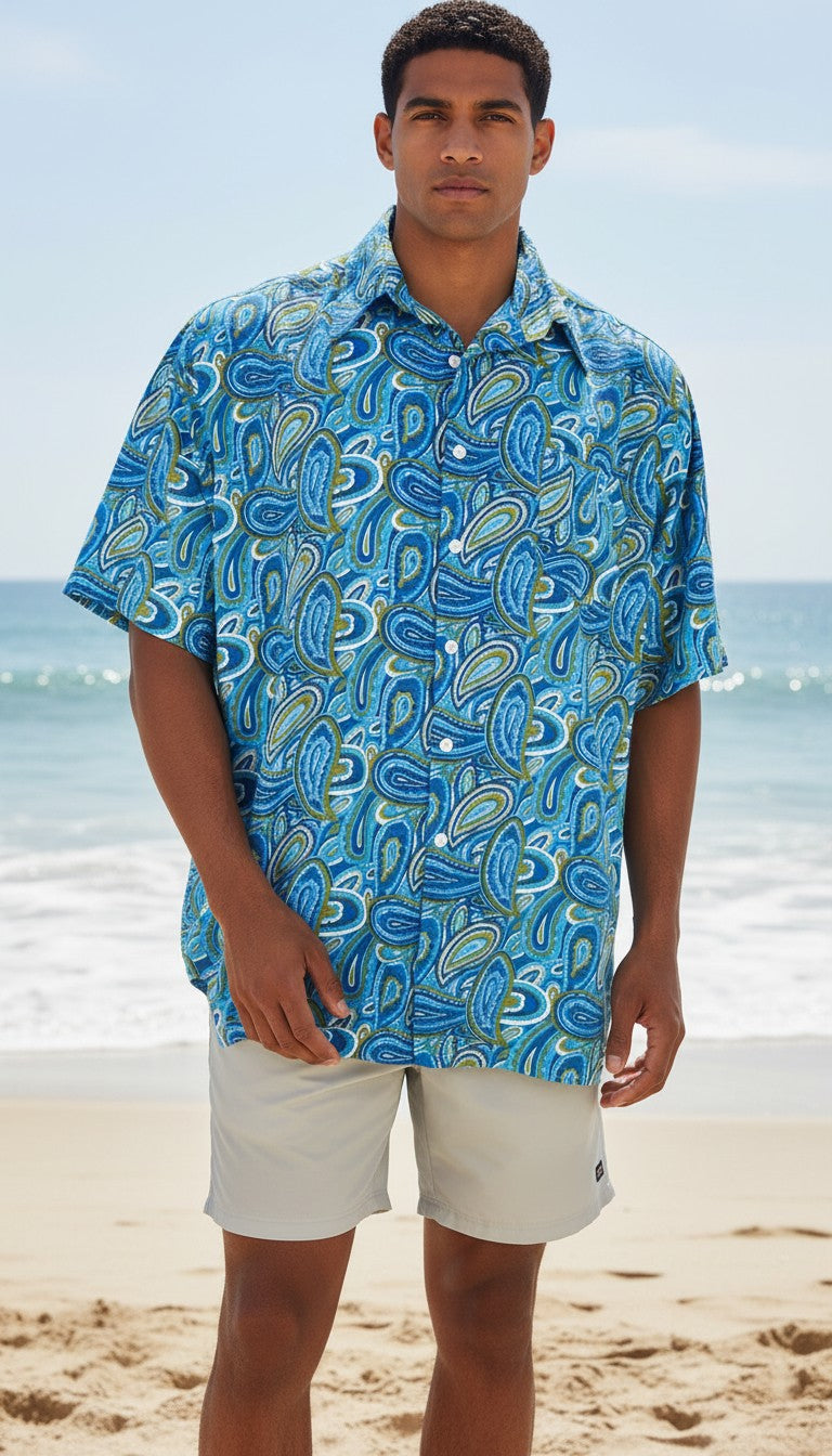 Chemise homme Frippindealz Kennington bleue à manches courtes avec motif paisley sur un mannequin à la plage
