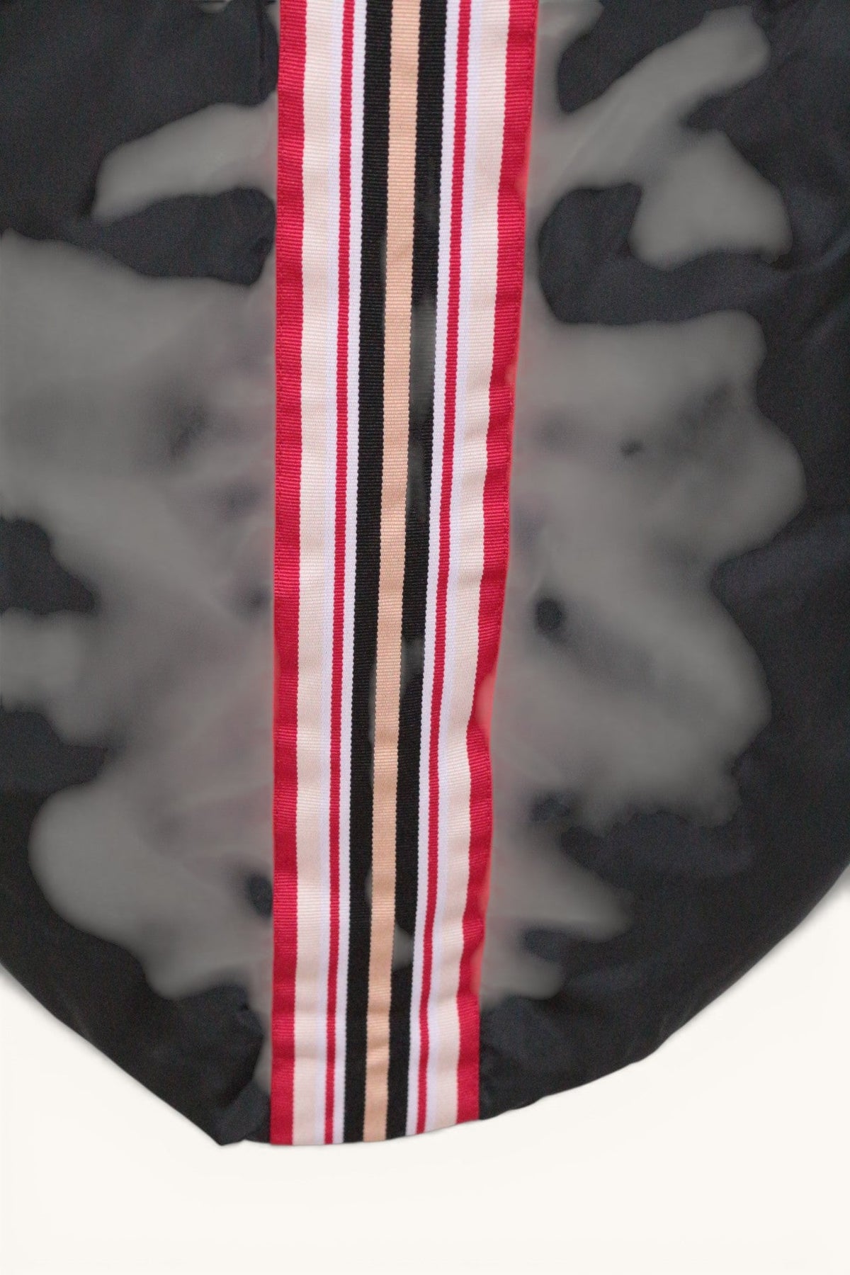 Détail de la bande rayée rouge, blanche et noire sur la doudoune longue noire Frippindealz
