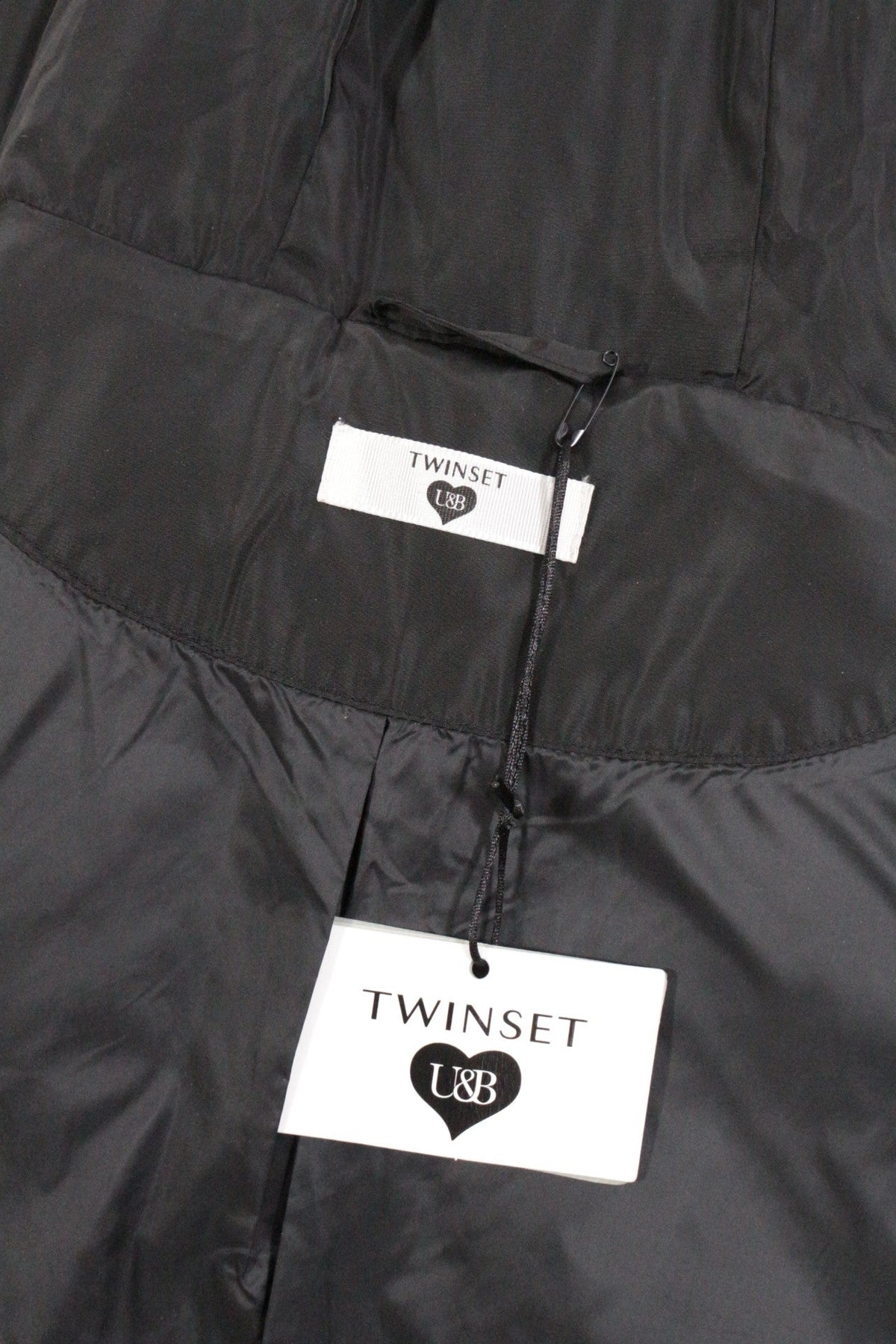 Détail de l'étiquette de marque TWINSET sur une doudoune longue noire neuve vendue par Frippindealz