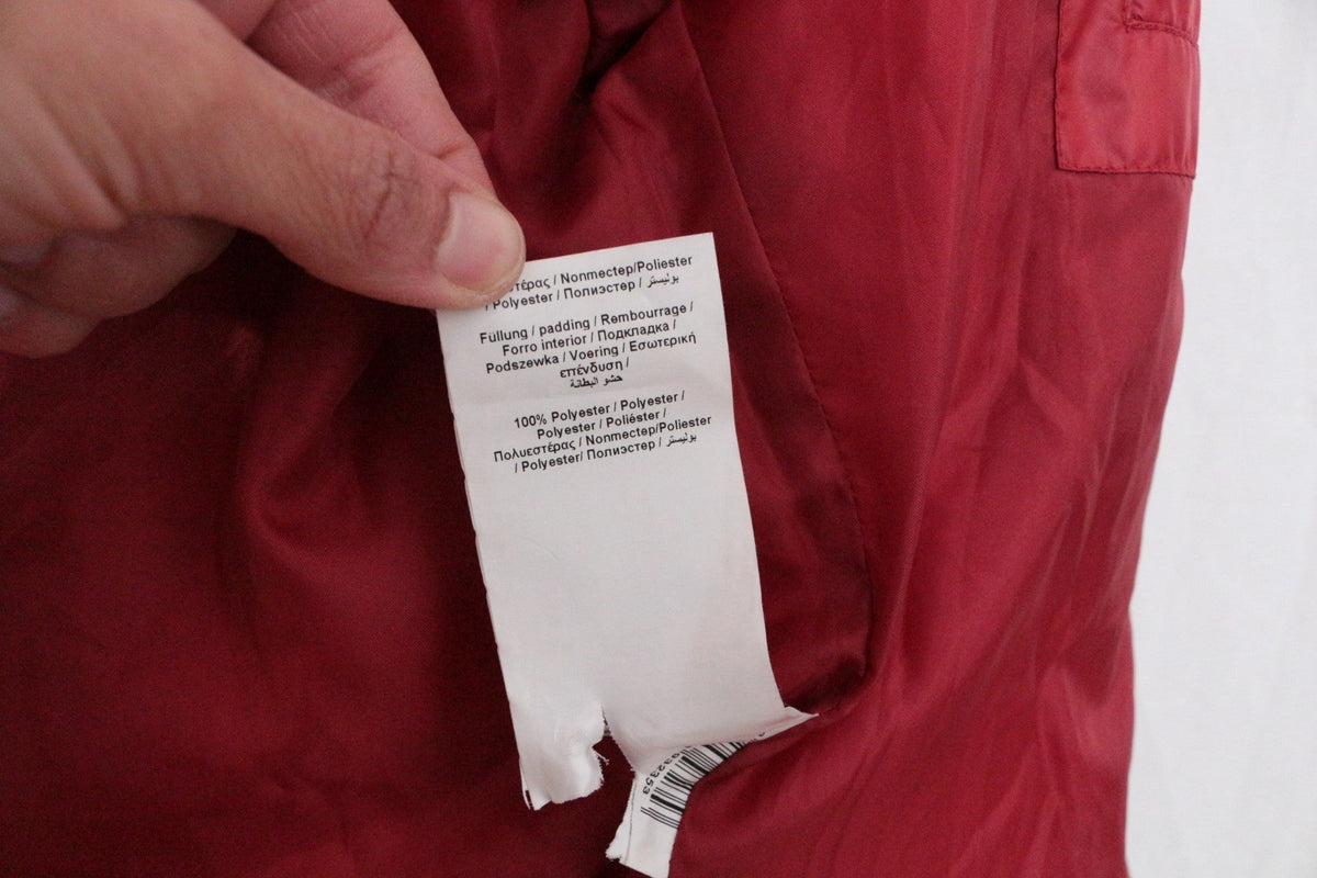 Étiquette de composition en polyester du manteau rouge Frippindealz, indiquant 100% polyester pour le rembourrage.