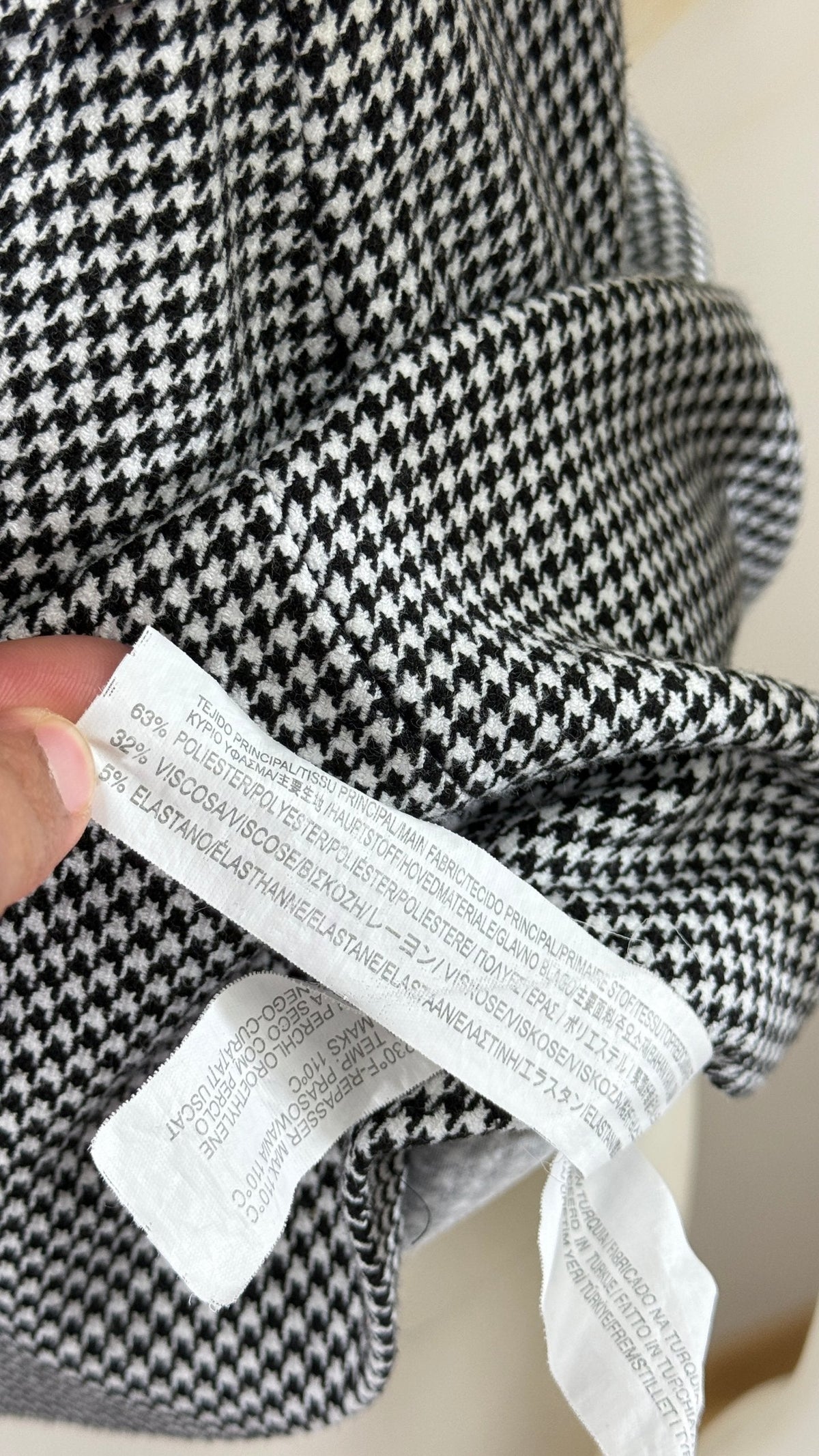 Étiquette de composition Frippindealz sur une robe à motif pied-de-poule noir et blanc en mélange polyester viscose