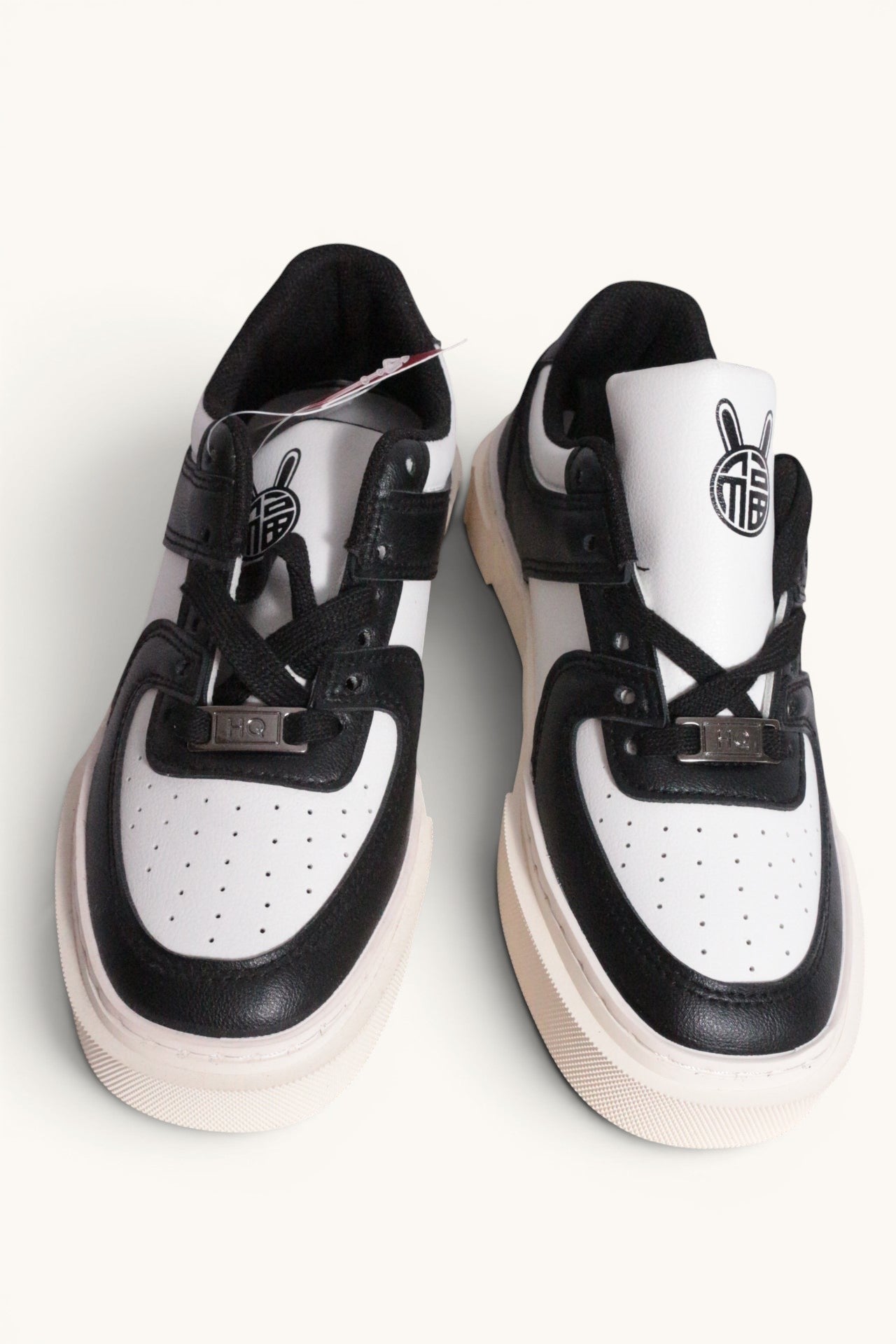 Frippindealz Baskets Huanqiu 1958 mixtes cuir synthétique blanc et noir avec logo lapin sur la languette.