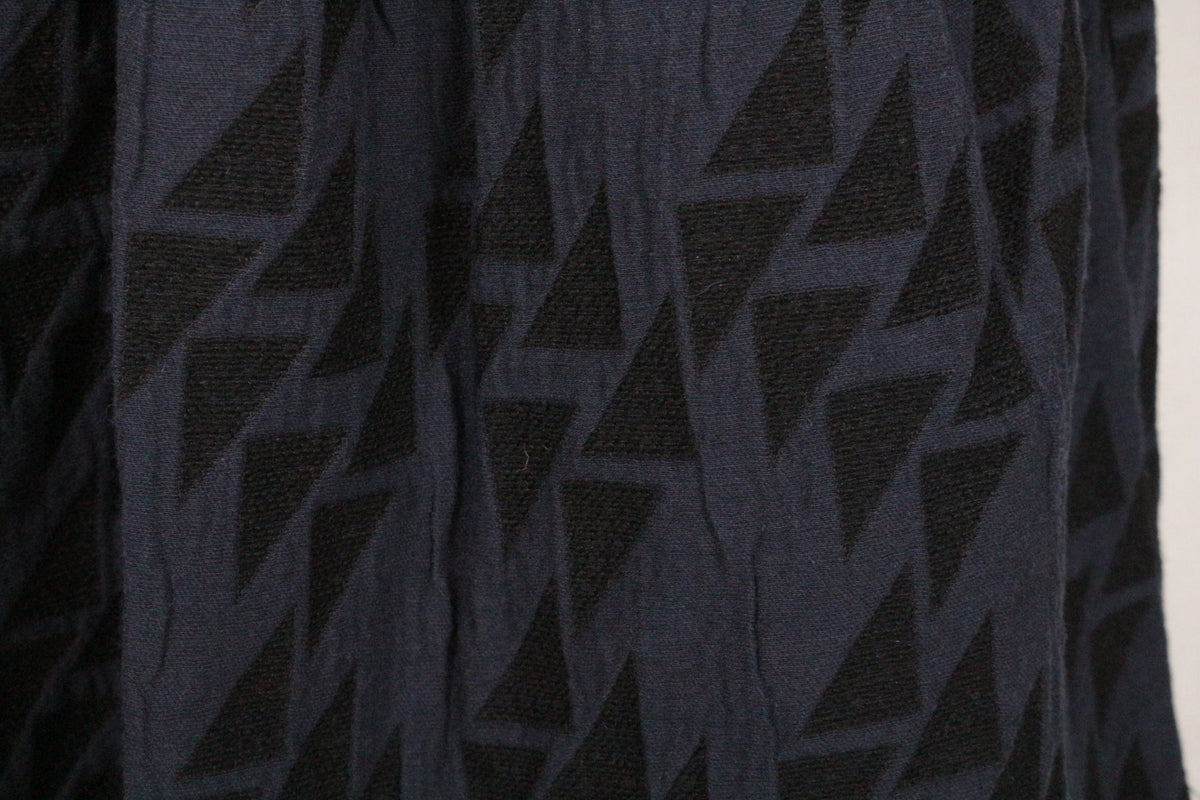 Gros plan sur le tissu bleu et noir de la jupe Frippindealz avec son motif géométrique triangulaire texturé