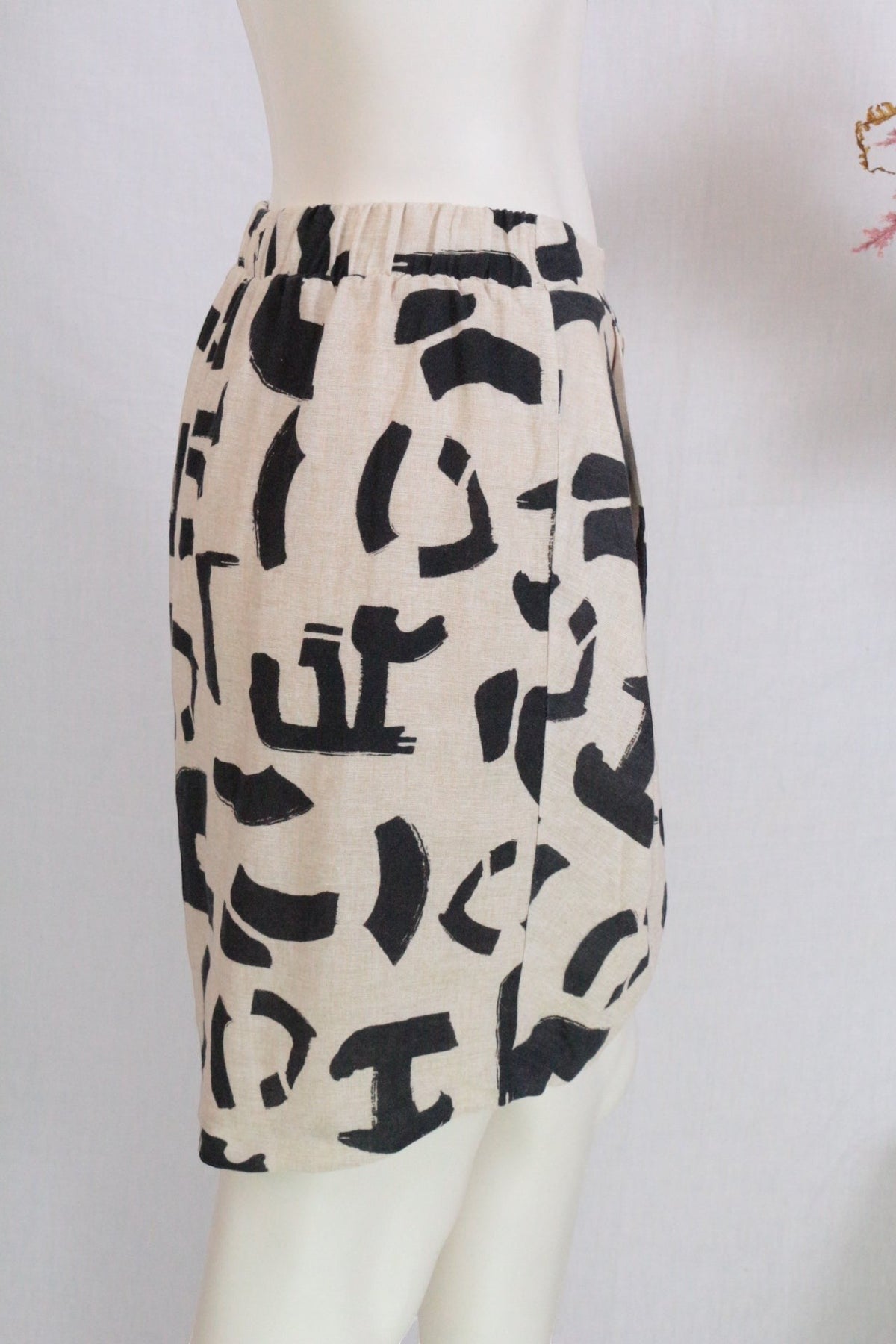 Jupe courte Frippindealz en lin et coton beige à motif abstrait noir, coupe ballon, vue de profil sur mannequin