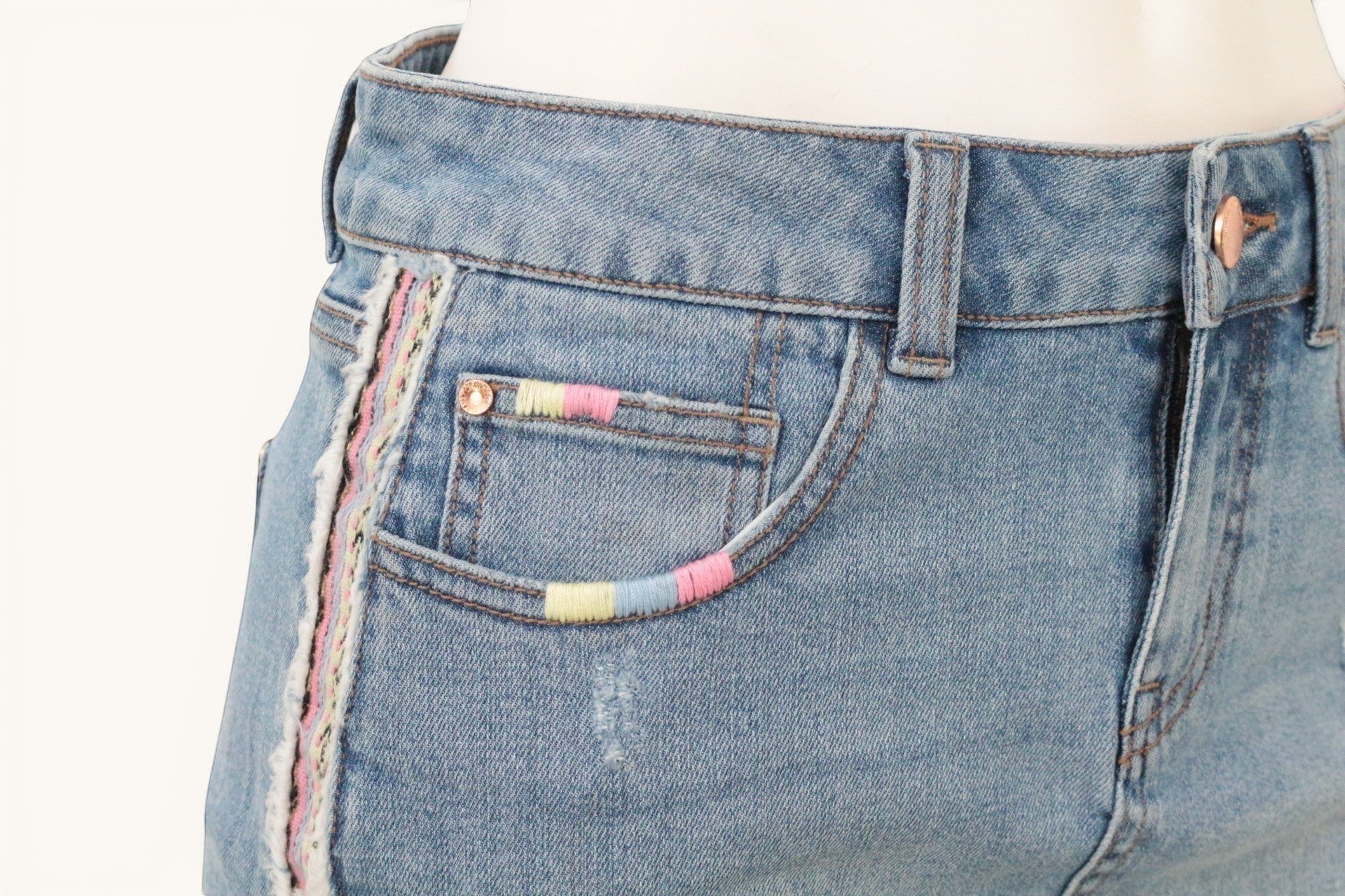 Frippindealz Jupe en jean bleu clair taille 38, broderies pastel sur les côtés et poches, finitions effilochées, style bohème.