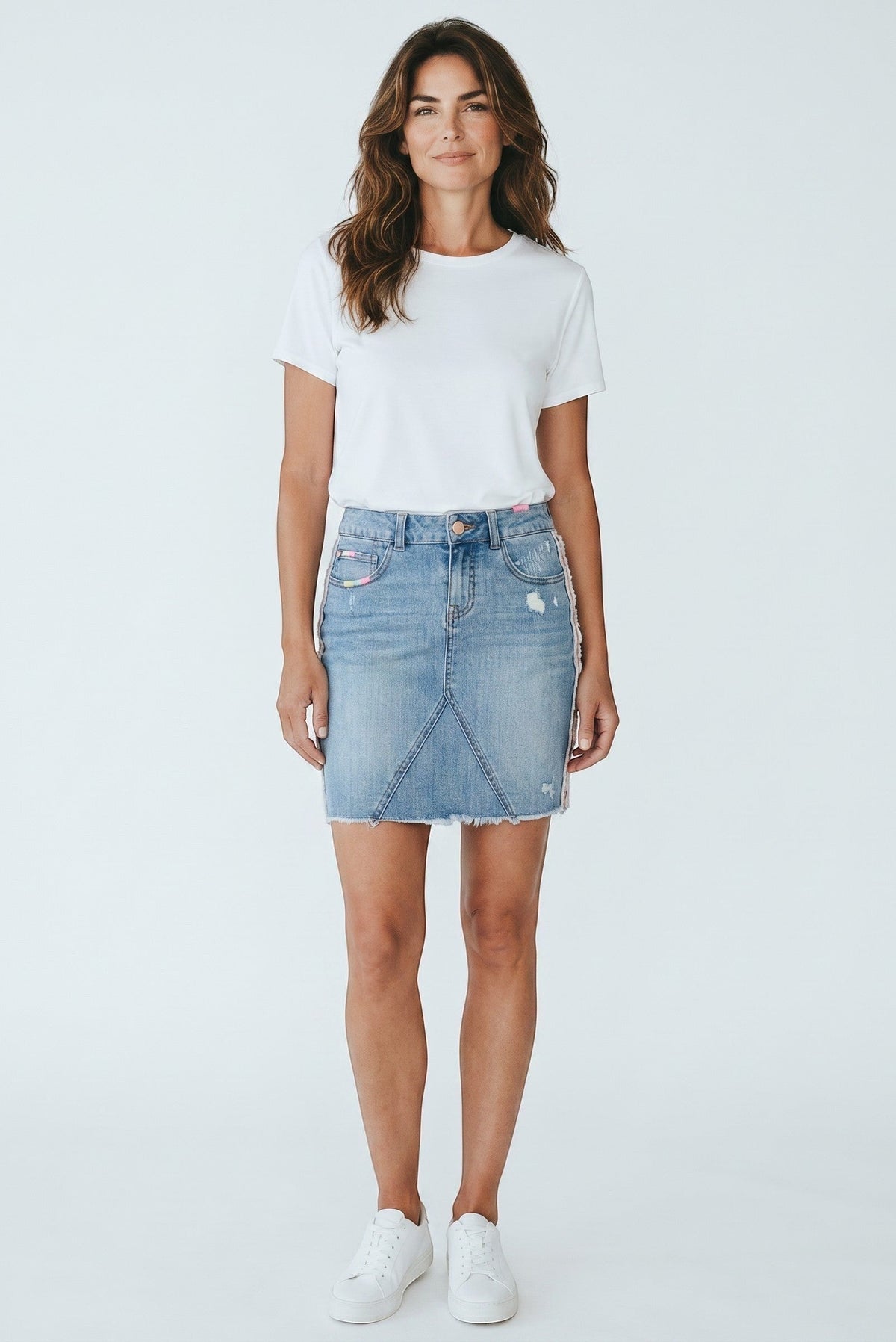 Modèle portant une jupe en jean Frippindealz bleu clair avec broderies pastel et finitions effilochées