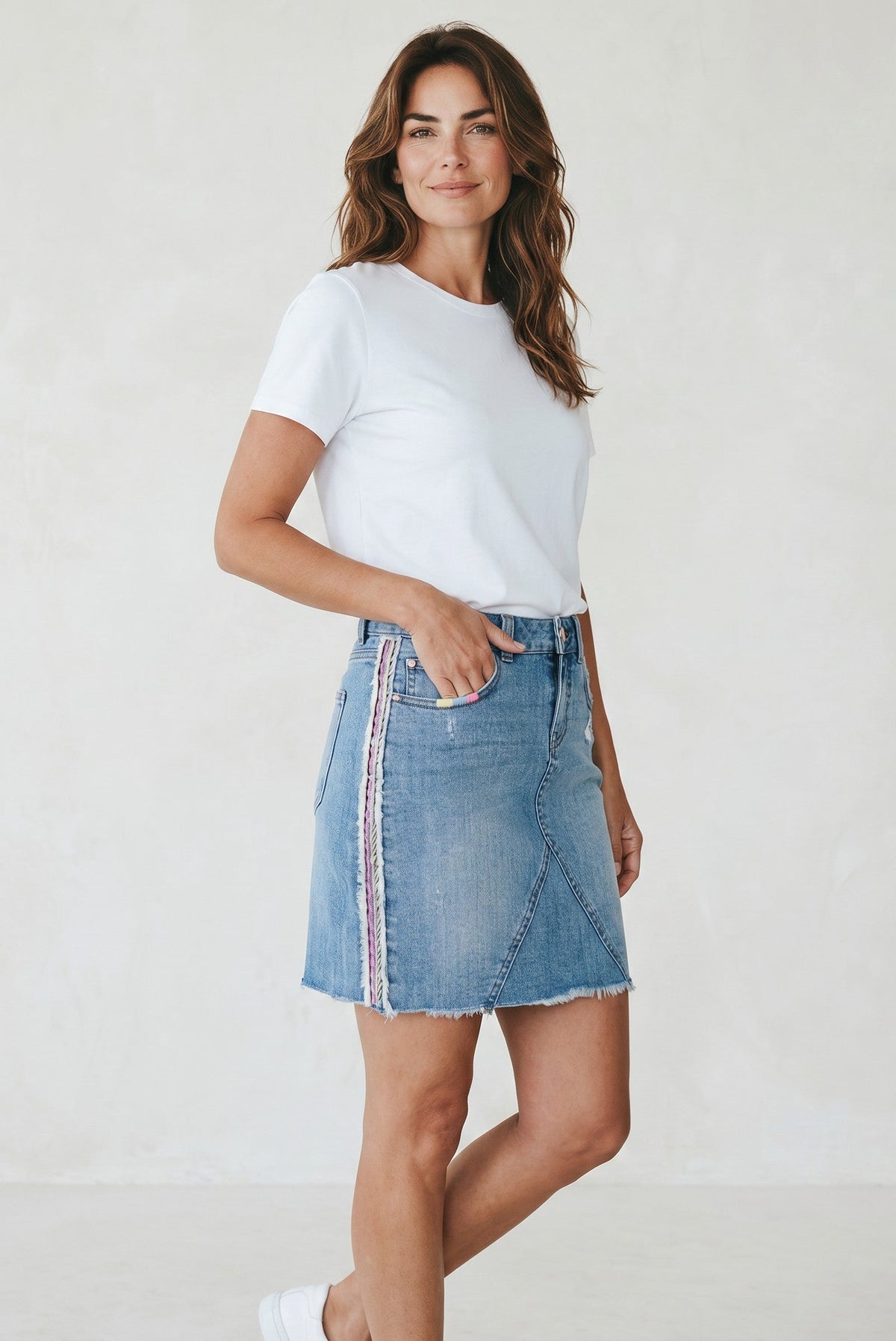 Modèle portant une jupe en jean Frippindealz bleu clair avec broderies pastel latérales et ourlet effiloché