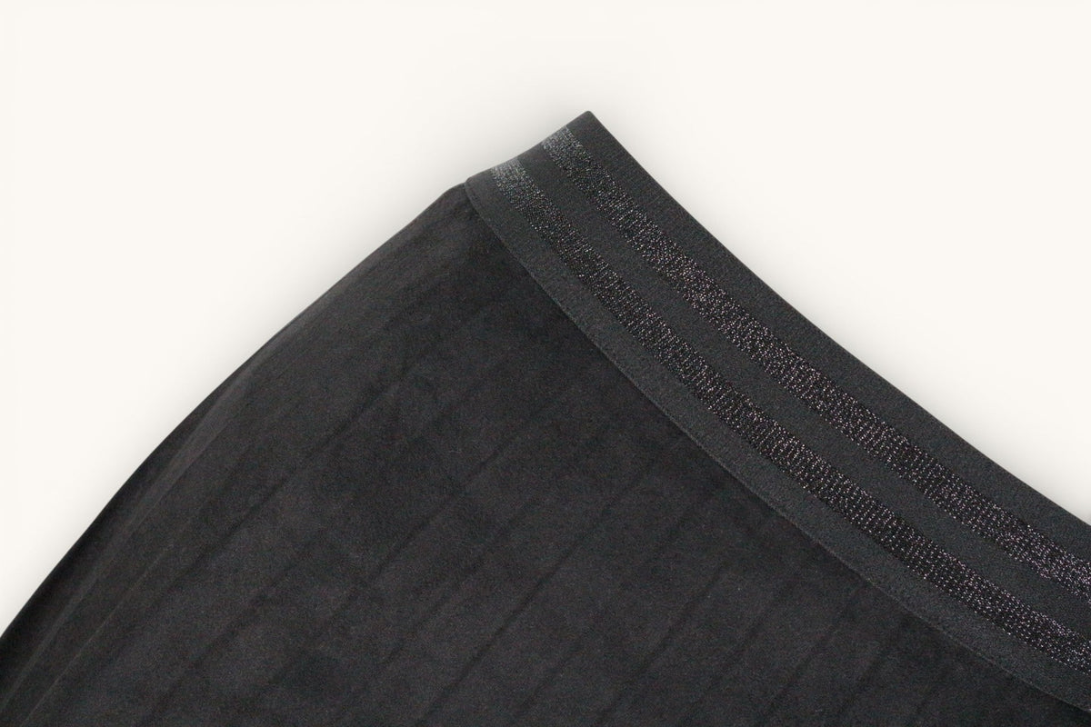 Gros plan sur la ceinture élastique scintillante d'une jupe noire Atmos de Frippindealz en polyester texturé