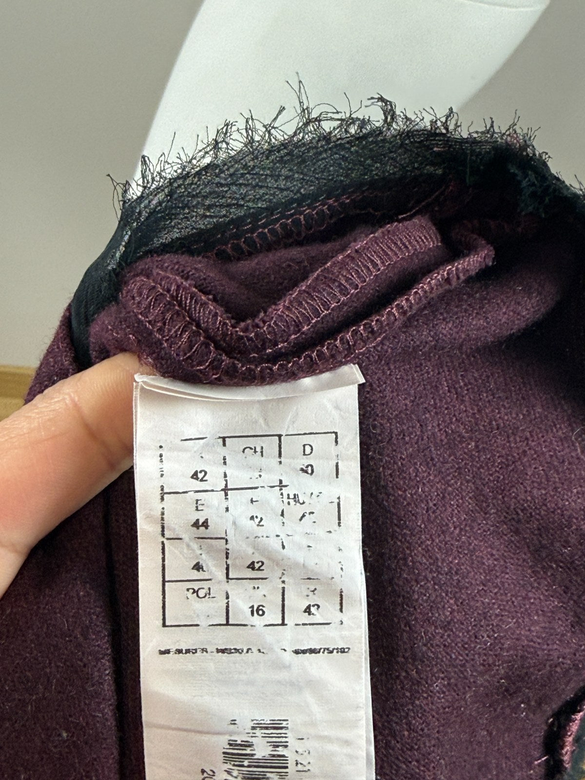 Etiquette de composition Frippindealz sur jupe midi Promod en laine bordeaux avec détails frangés noirs