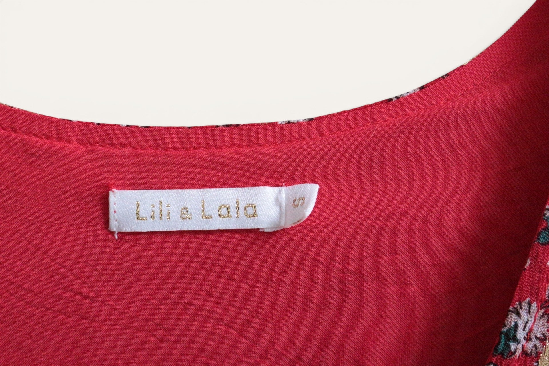 Gros plan sur l'étiquette de la robe courte Frippindealz Lili & Lala en polyester rouge avec détails dorés