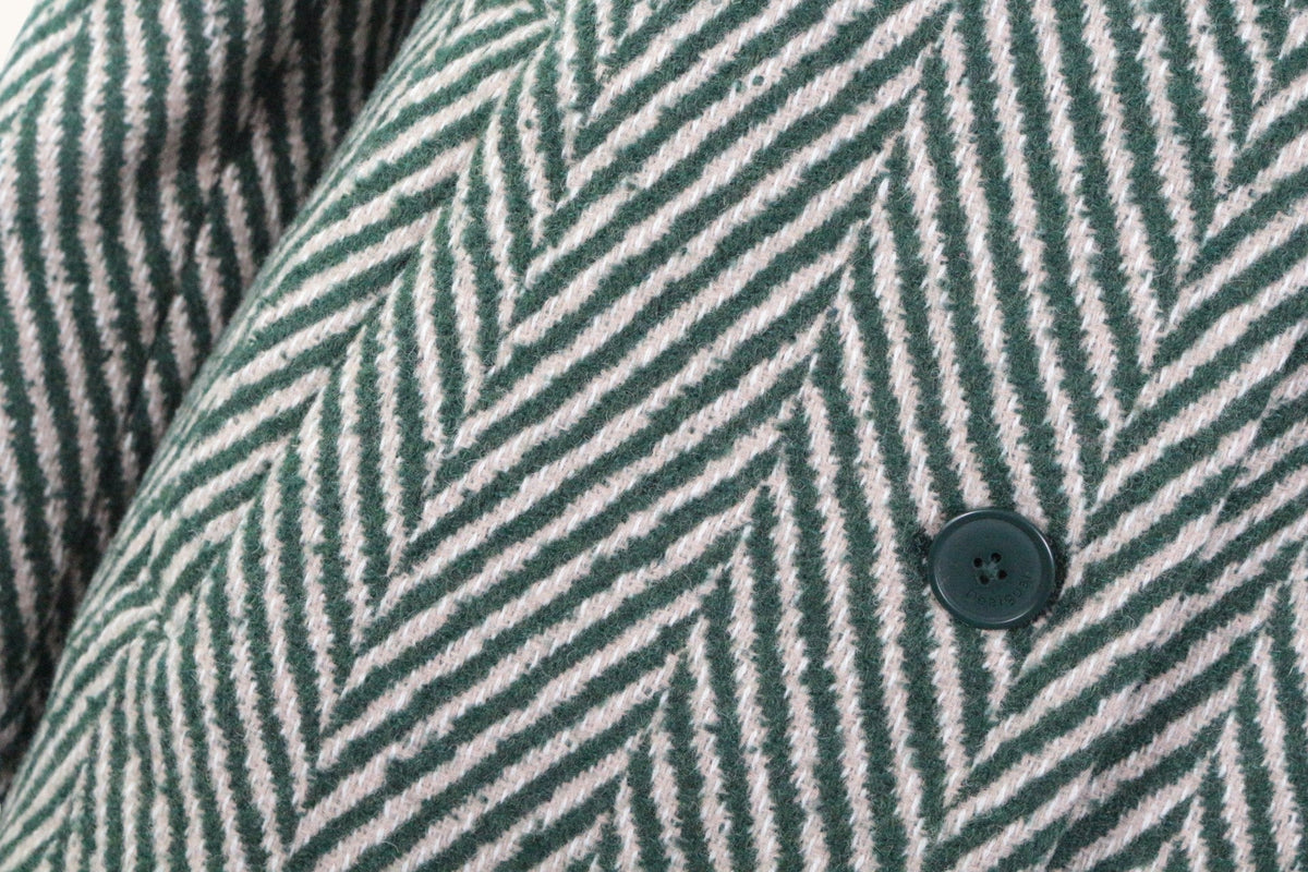 Gros plan sur le motif chevron vert et beige du manteau en laine Desigual chez Frippindealz avec bouton gravé
