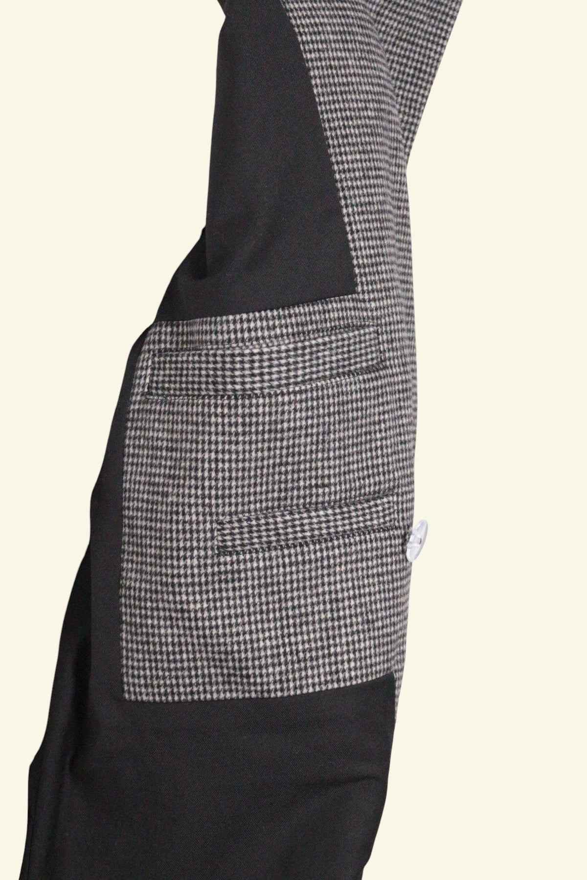 Gros plan sur la poche d'un manteau Frippindealz mi-long en laine et polyester, motif pied-de-poule noir et gris.