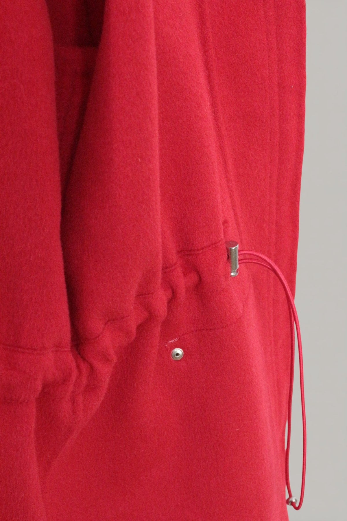 Détail du cordon de serrage à la taille sur un manteau en laine rouge vif Frippindealz