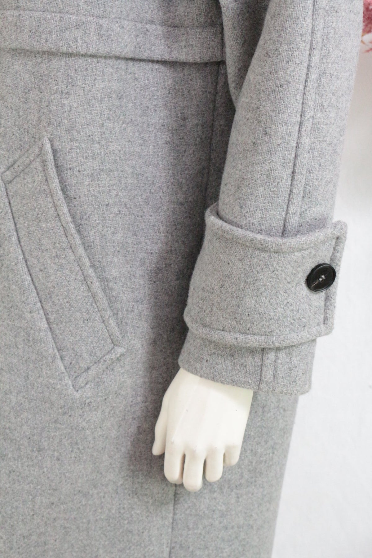 Détail de la manche d'un manteau long gris Frippindealz en laine avec patte boutonnée et poche passepoilée