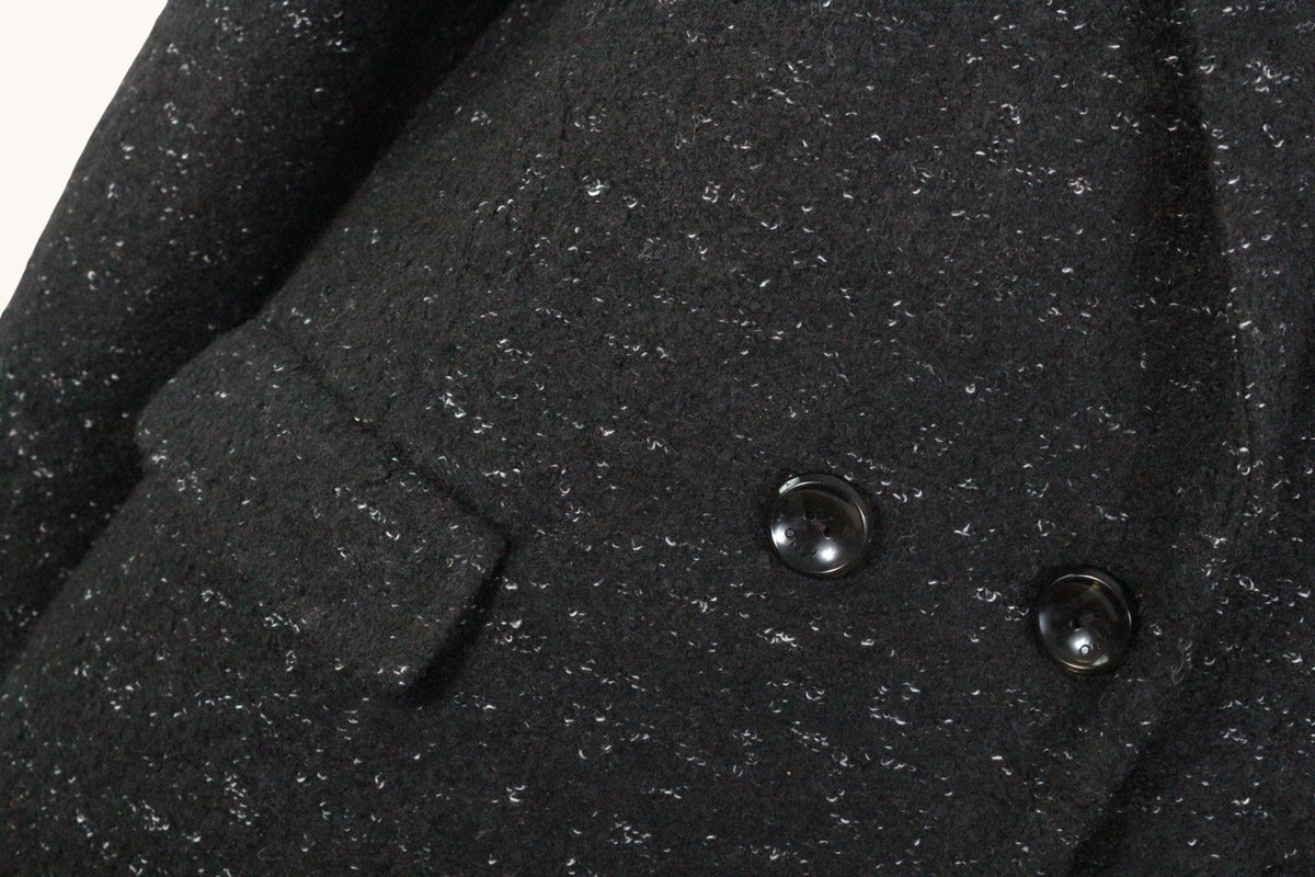 Gros plan sur le manteau noir Frippindealz en laine et polyester avec texture mouchetée et boutons élégants