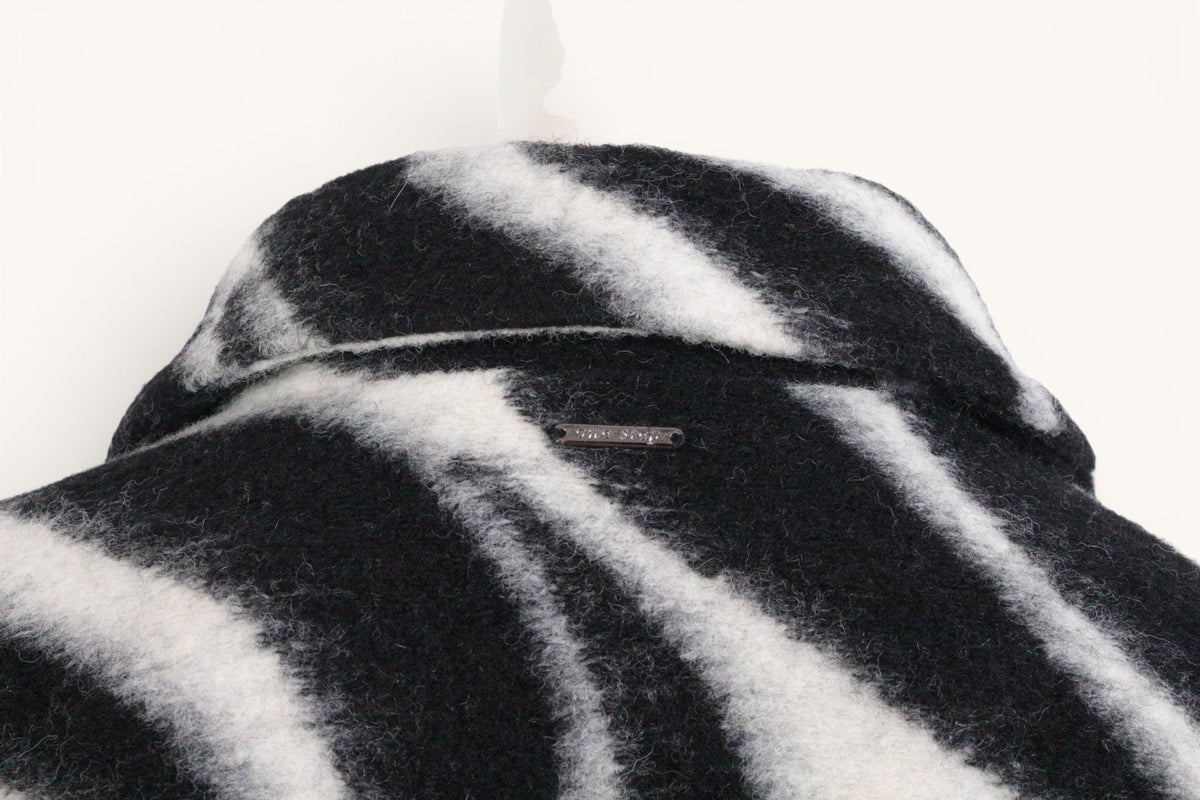 Détail du col du manteau Frippindealz en laine et polyester à motif zébré noir et blanc
