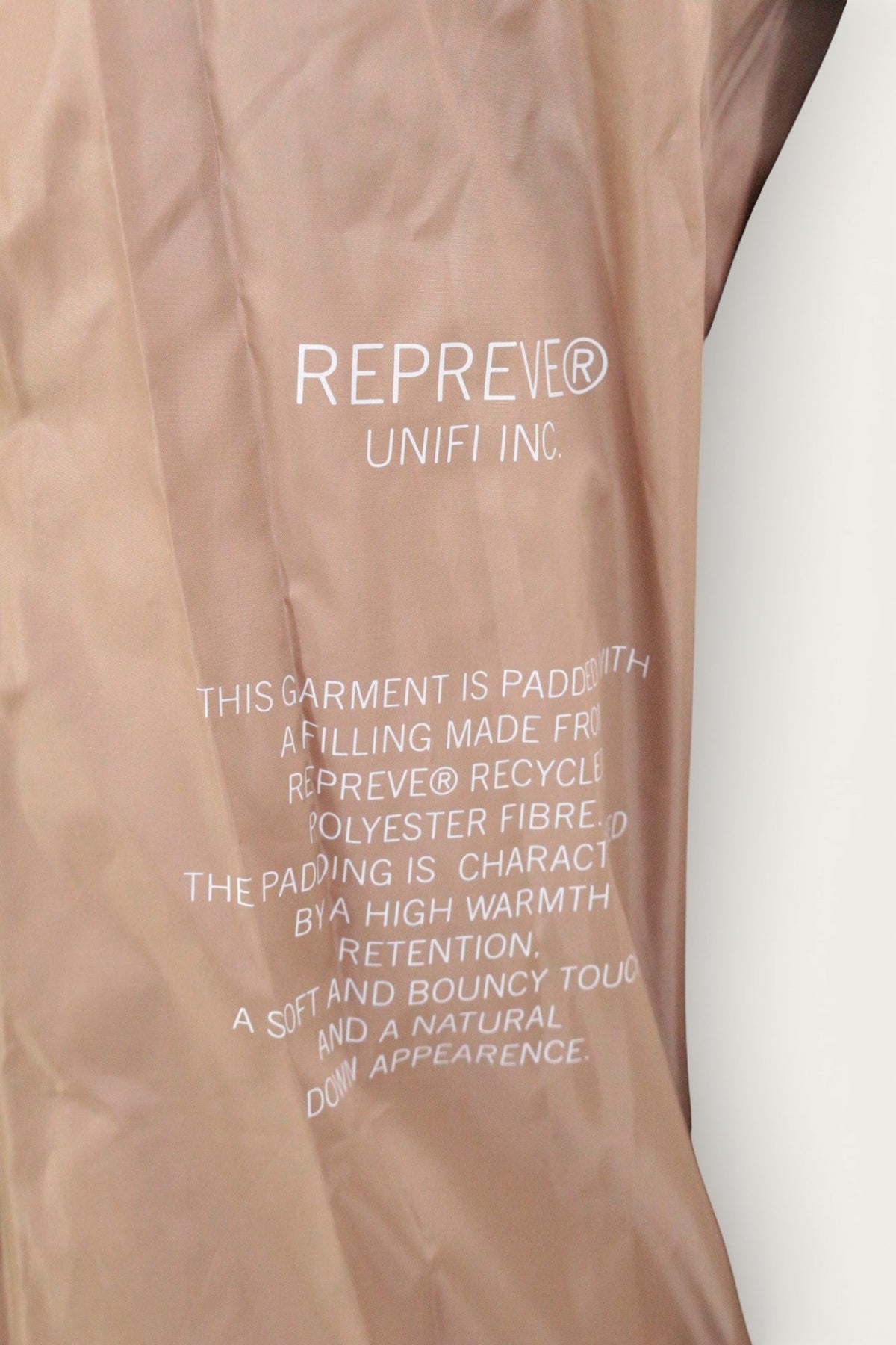 Détail de la doublure beige d'une doudoune Frippindealz Marc O Polo avec inscription sur le rembourrage recyclé