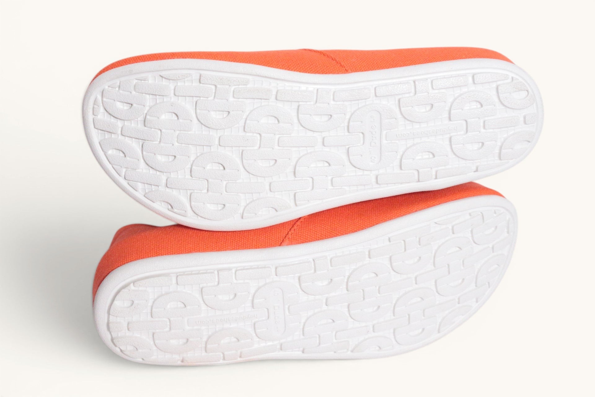 Chaussures mocassins Hey Dude en textile orange vif, semelle blanche texturée, confortables et légères.