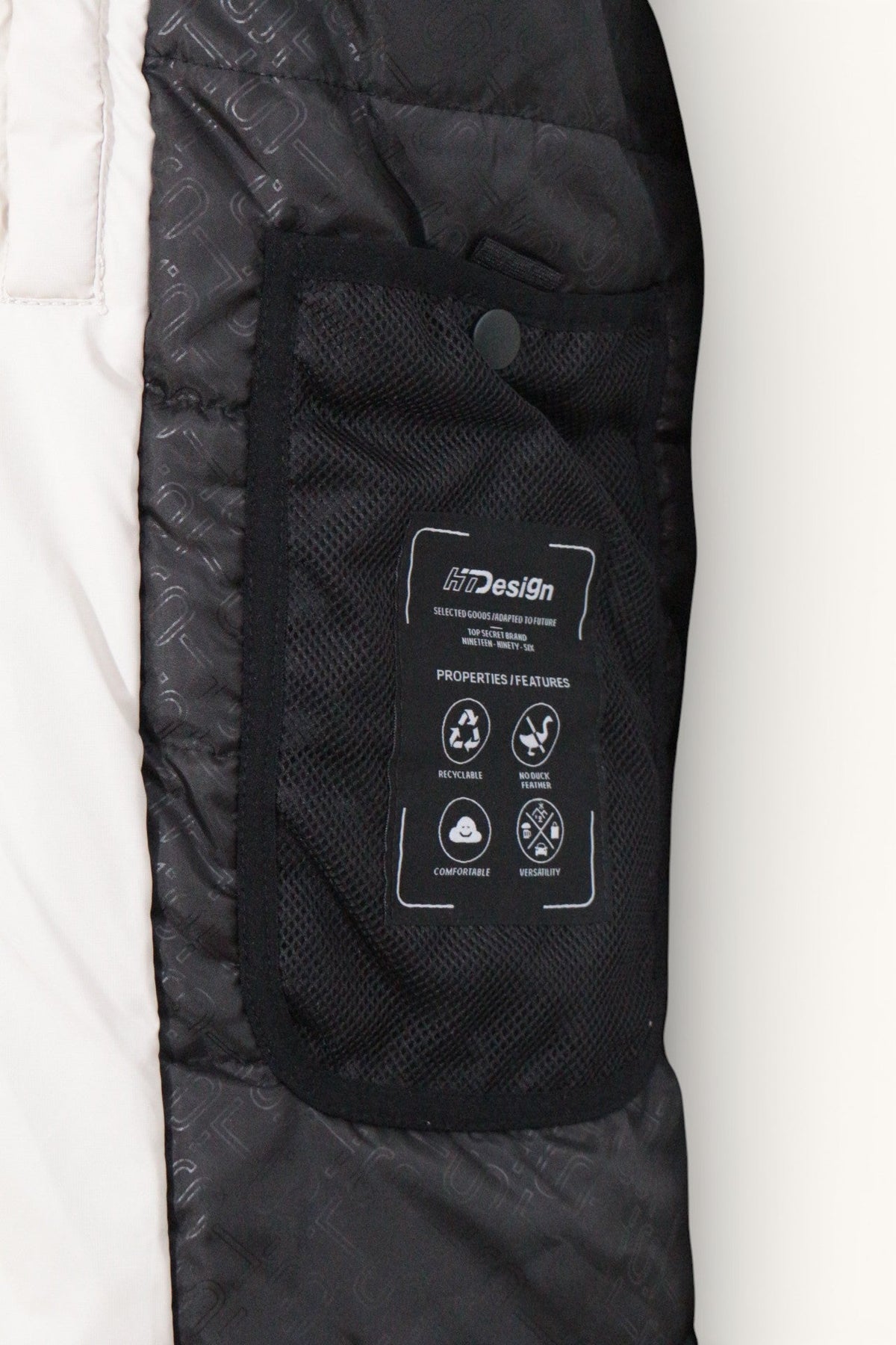 Détail intérieur d'une parka Frippindealz noire et blanche avec poche en filet et étiquette technique H7Design