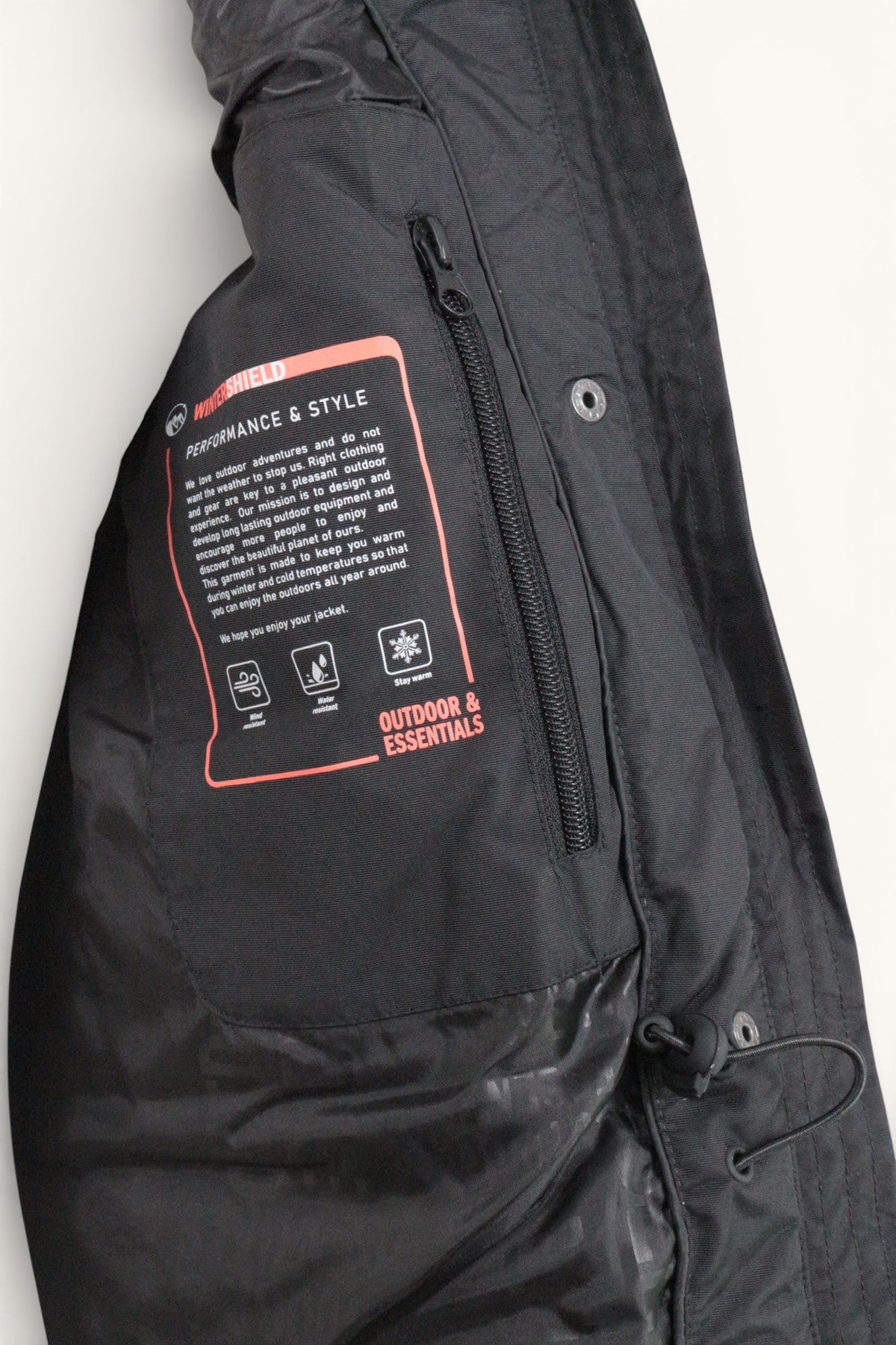 Détail intérieur d'une parka Frippindealz noire avec étiquette technique Wintershield et poche zippée
