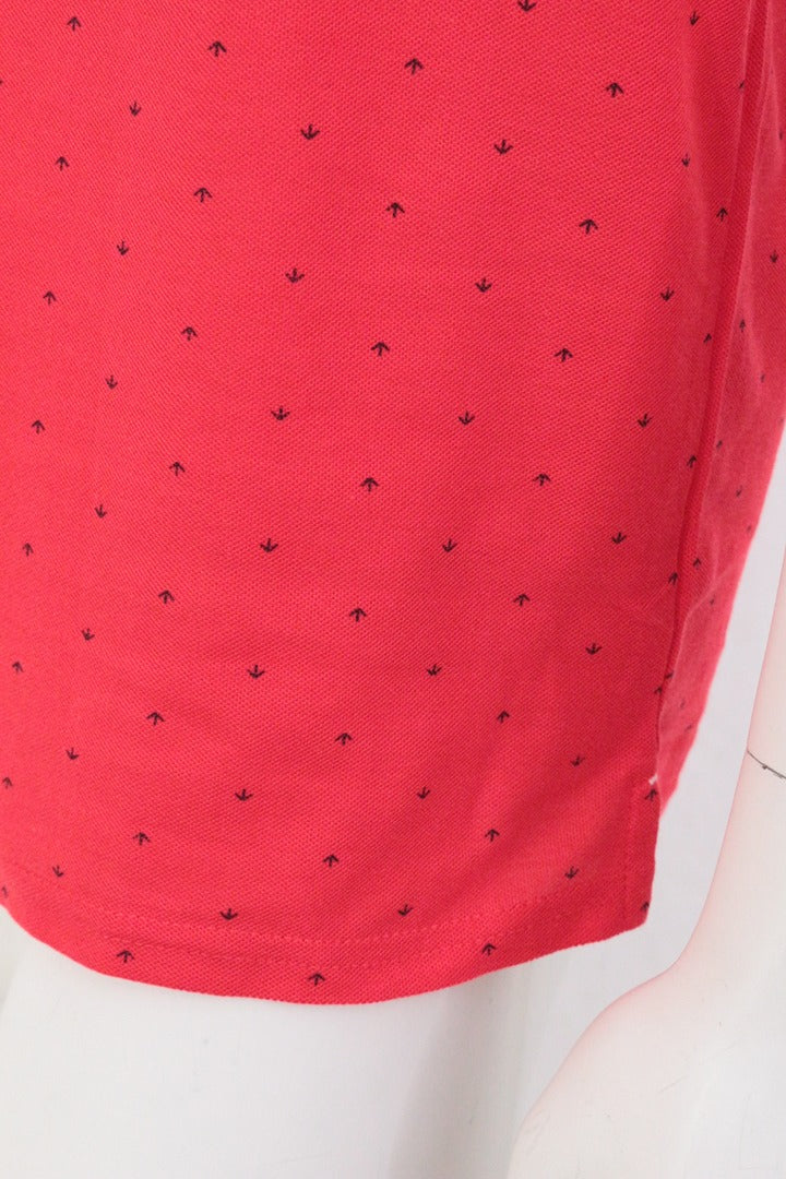 Gros plan sur le tissu piqué rouge d'un polo Frippindealz avec un motif imprimé discret et une texture respirante