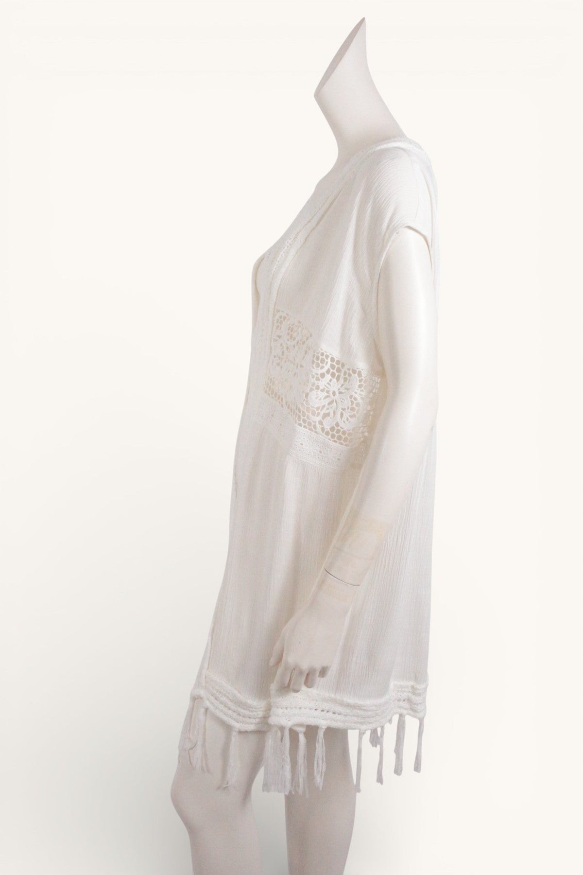Poncho Béré Frippindealz en dentelle aérienne couleur écru avec détails ajourés et franges, vue de profil