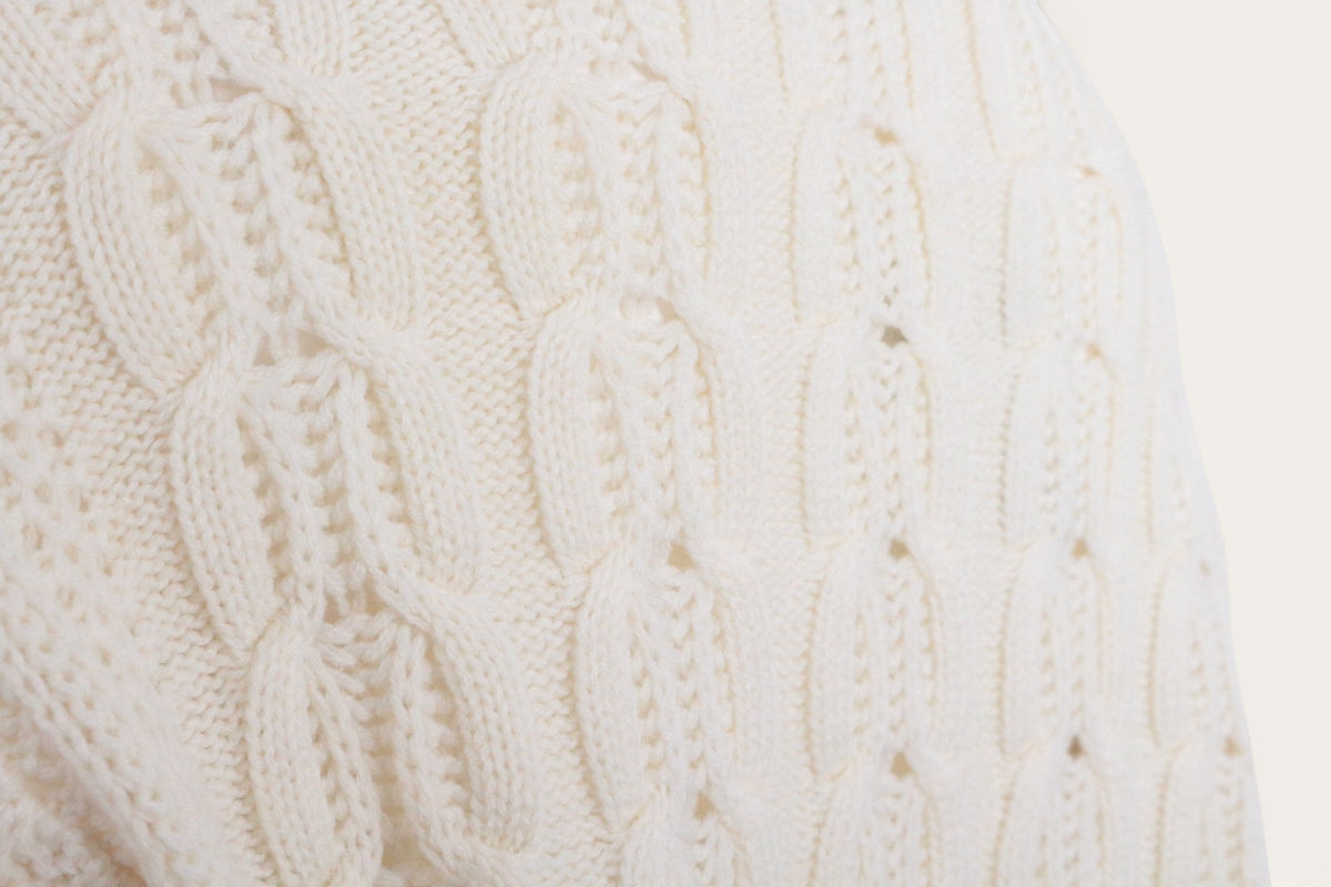 Gros plan sur la maille torsadée crème d'un pull en laine Frippindealz, texture douce et élégante.