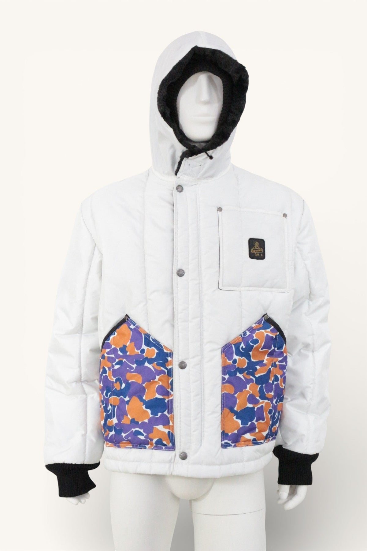 Veste d'hiver Frippindealz Refrigiwear blanche avec poches camouflage multicolores, capuche doublée et poignets noirs.