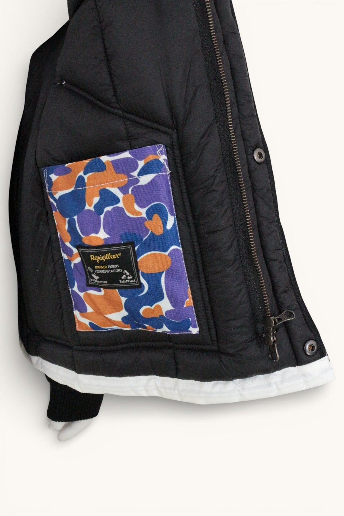 Détail intérieur d'une veste Frippindealz Refrigiwear avec doublure matelassée noire et poche à motif camouflage