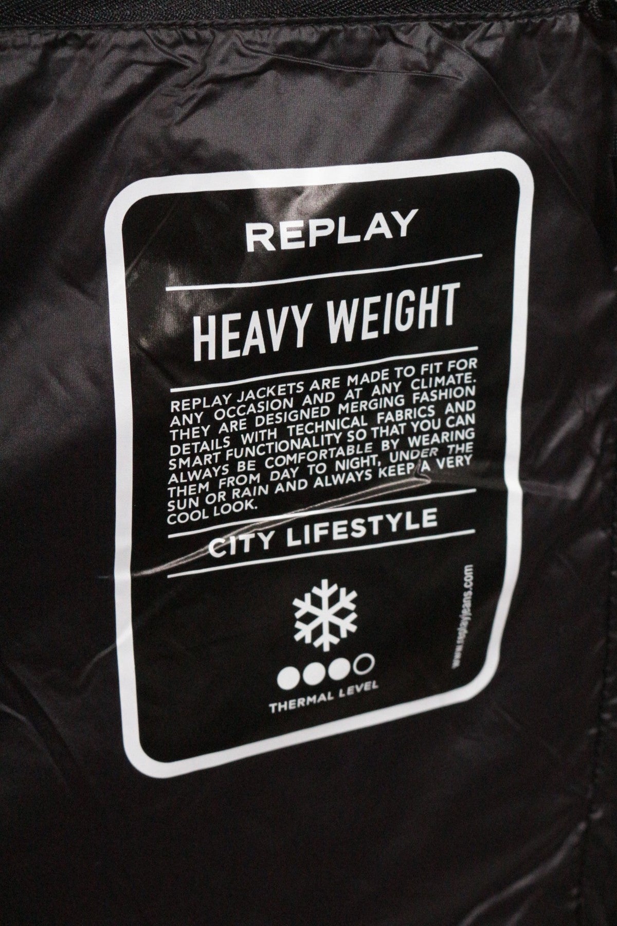 Étiquette intérieure noire de doudoune Frippindealz Replay indiquant Heavy Weight et City Lifestyle