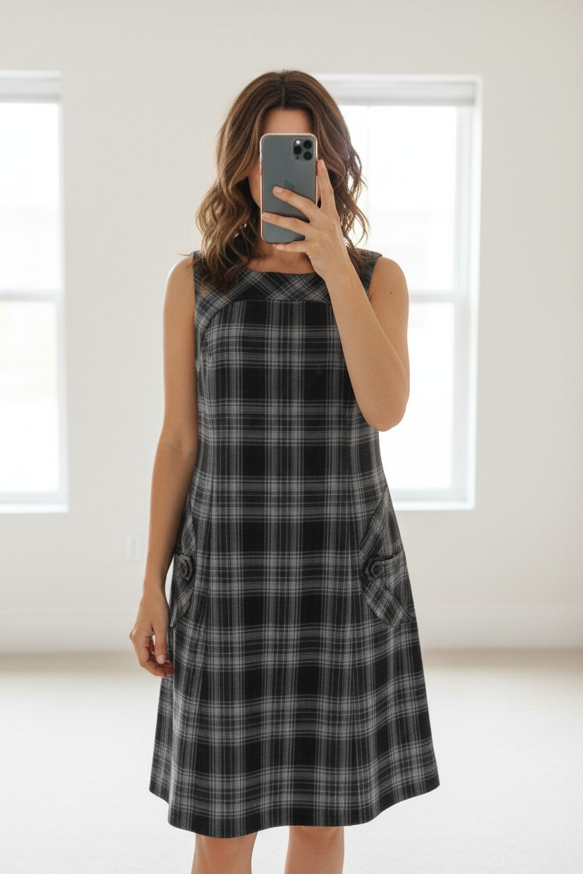 Robe Caroll à carreaux noirs et gris en polyester et viscose, sans manches, avec poches boutonnées. Fabriquée en France.