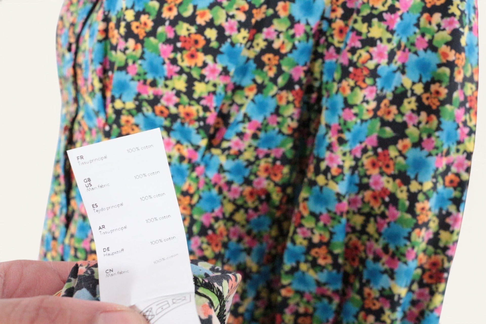 Gros plan sur l'étiquette de composition en coton d'une robe longue à fleurs Frippindealz sur fond noir