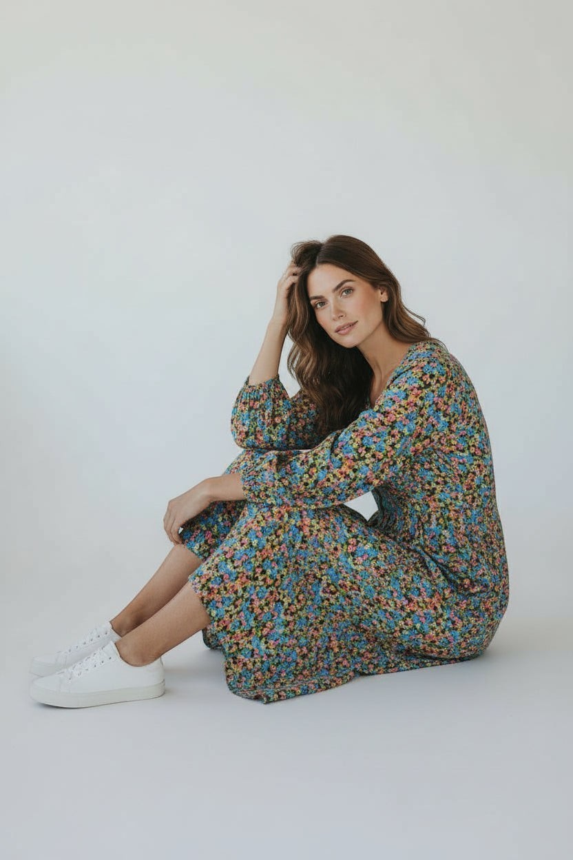 Modèle portant une robe longue Frippindealz à imprimé floral multicolore avec manches amples sur fond blanc