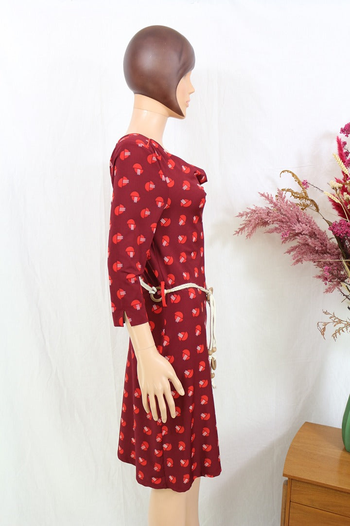 Robe midi Frippindealz Zoë Loveborn bordeaux à motif géométrique, col bénitier et ceinture fine, vue de profil.