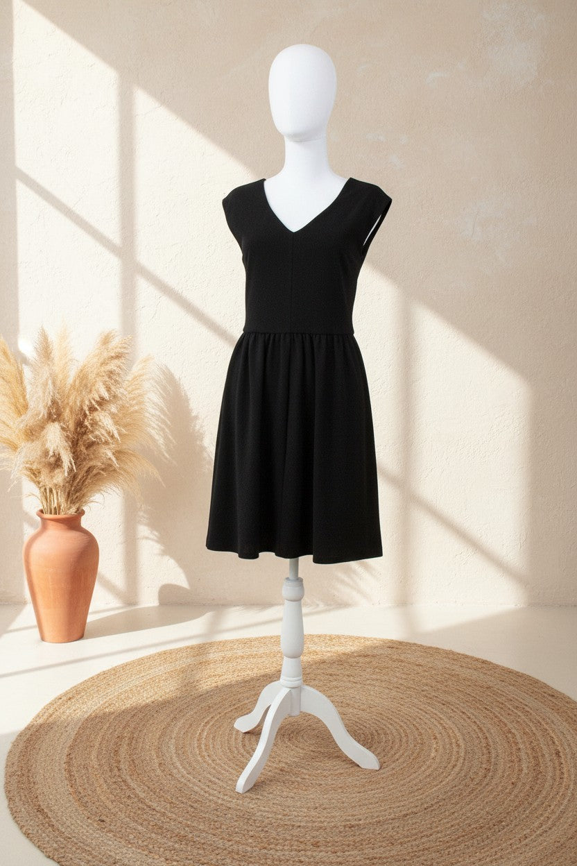 Robe midi noire Frippindealz en polyester avec encolure en V, présentée sur un mannequin dans un décor bohème.