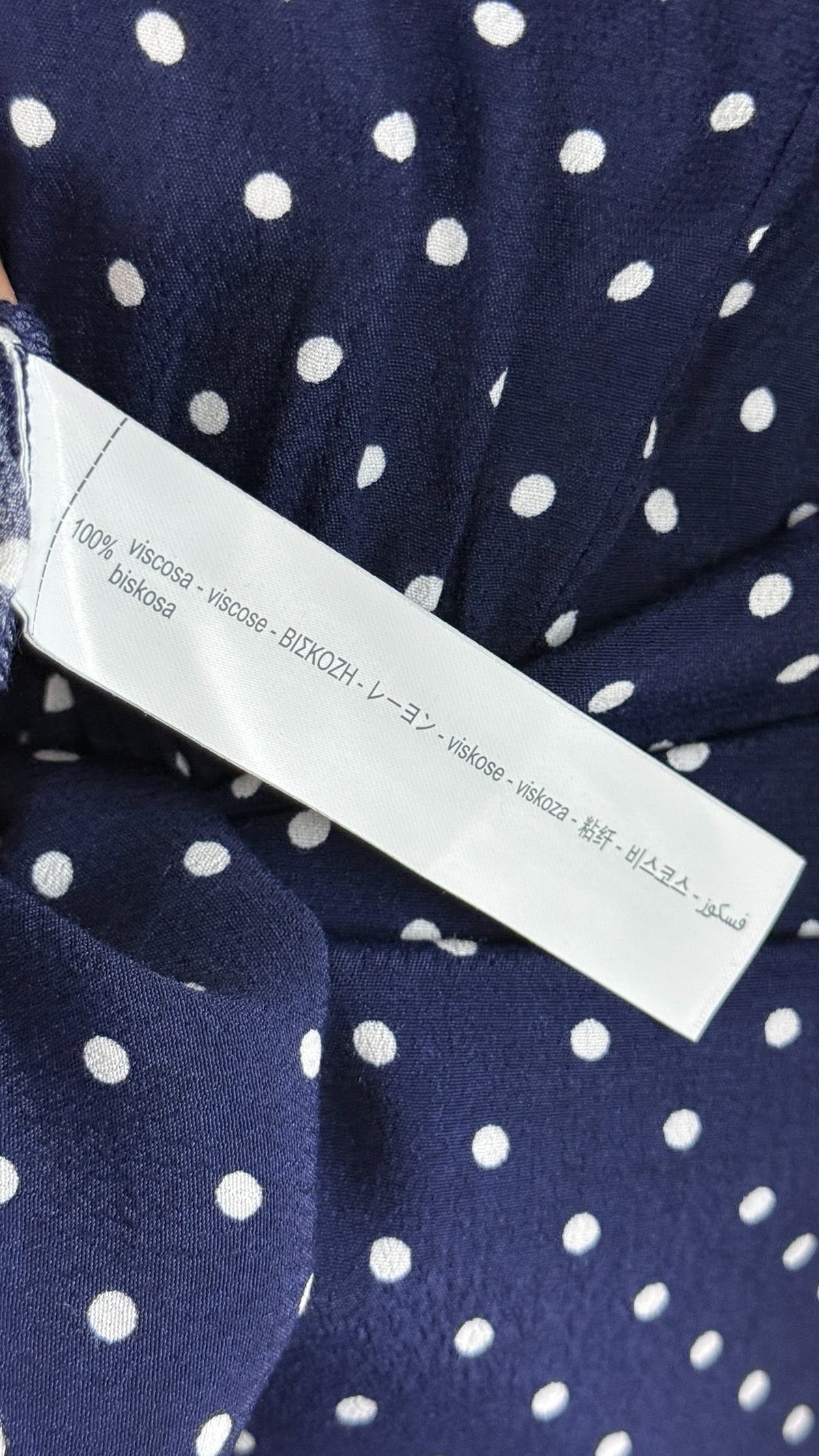 Etiquette de composition 100% viscose sur robe courte Frippindealz bleu marine à pois blancs