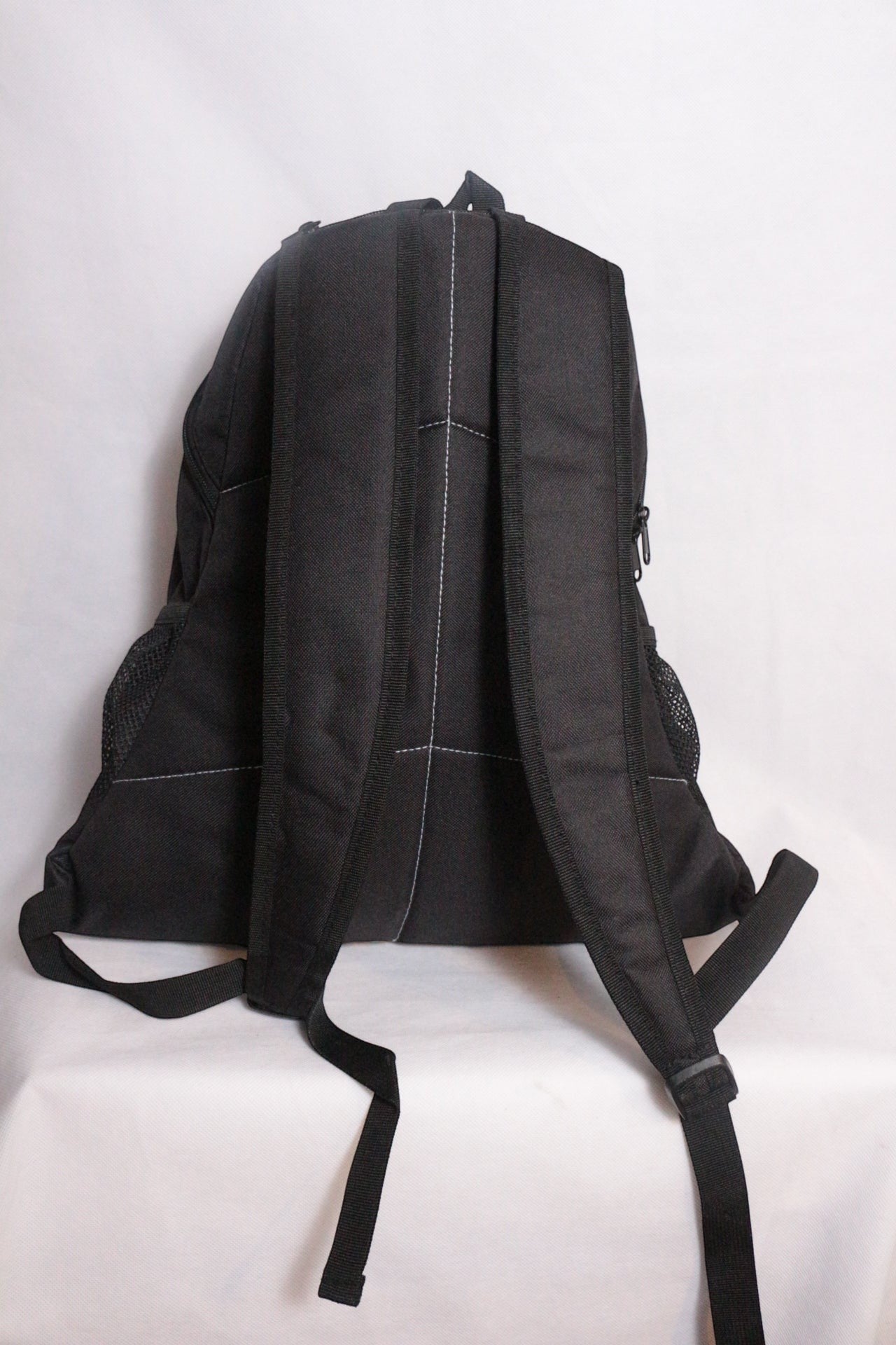 Sac à dos Enuff Skateboards noir en polyester avec coutures blanches contrastantes, poches latérales en filet, idéal pour le quotidien.