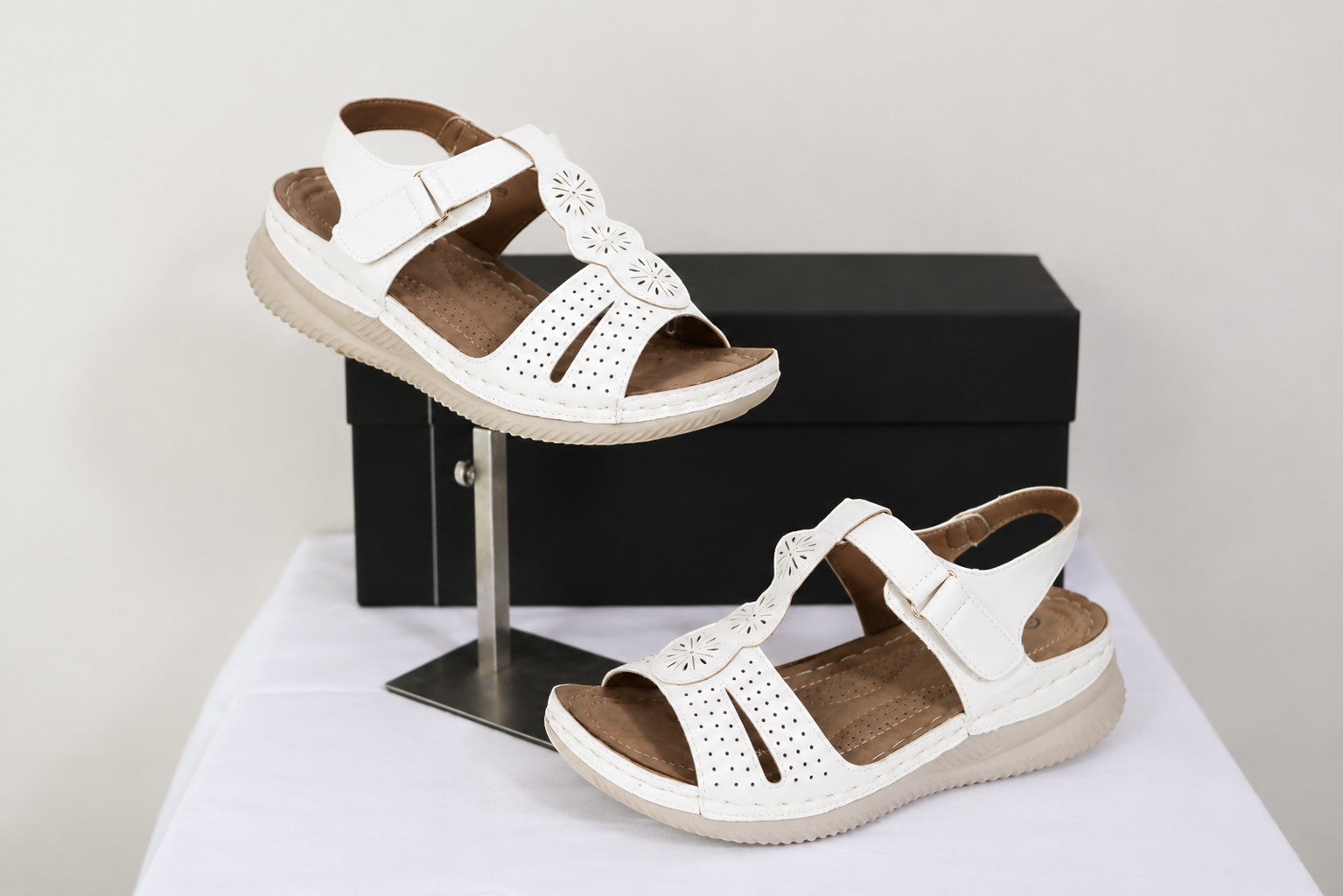 Sandales confort femme Frippindealz blanches avec brides ajustables, détails ajourés floraux et semelle compensée.